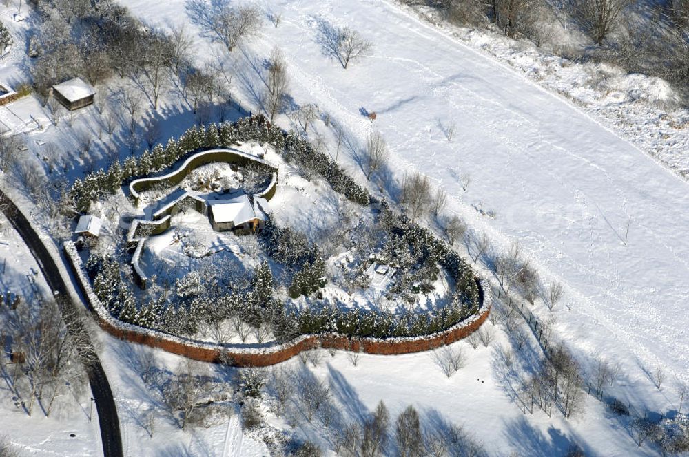 Aerial photograph Berlin - Blick auf den Japanischen Garten im winterlich verschneiten Chinesischen Garten im Erholungspark Marzahn. Der Erholungspark Marzahn liegt im Berliner Bezirk Marzahn-Hellersdorf am nördlichen Fuß des Kienbergs und wurde am 9. Mai 1987 anlässlich der 750-Jahr-Feier von Berlin als Berliner Gartenschau und Geschenk der Gärtner an die Hauptstadt der DDR (Ost-Berlin) eröffnet und sollte somit ein Gegenstück zum Britzer Garten im damaligen West-Berlin darstellen. 1991 wurde die Berliner Gartenschau nicht nur in Erholungspark Marzahn umbenannt, sondern auch umgebaut: Große Spiel- und Liegewiesen sowie neue Spielplätze entstanden, Bäume wurden gepflanzt und Sondergärten überarbeitet und erweitert. Der neu gestaltete Park sollte den 300.000 Bewohnern der umliegenden Großsiedlungen als vielfältig nutzbare Erholungslandschaft dienen. Seit Oktober 2000 ist diese durch ihre Gärten der Welt auch weit über die Stadtgrenzen hinaus bekannt. 2005 wurde der Chinesische Garten im Erholungspark Marzahn als drittschönste Parkanlage Deutschlands ausgezeichnet. Außerdem gehört der Erholungspark zu den 365 Orten im Land der Ideen.