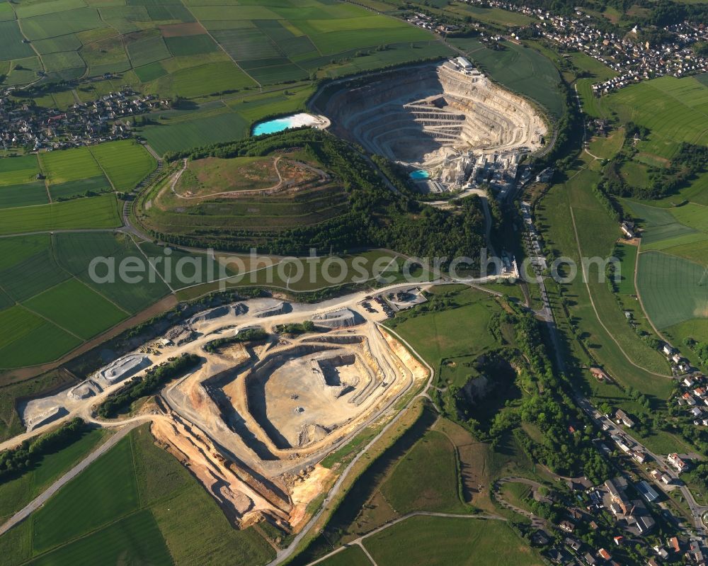 Aerial image Hahnstätten - Quarry-pit in the North of the borough of Hahnstaetten in the state of Rhineland-Palatinate. The borough and municipiality is located in the county district of Rhine-Lahn. The agricultural village consists of residential buildings and areas, is an official tourist resort and is surrounded by meadows and fields. A chalk-pit and limestone quarry is located in the North of the borough