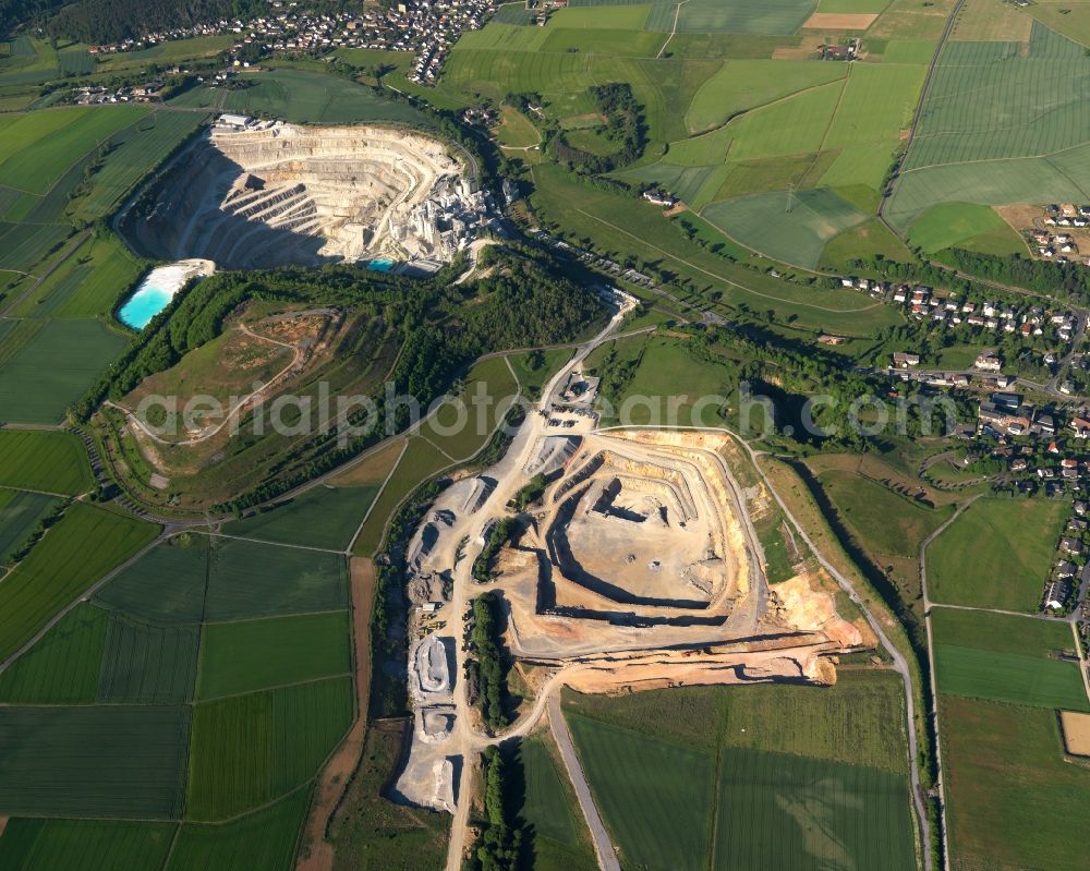 Aerial photograph Hahnstätten - Quarry-pit in the North of the borough of Hahnstaetten in the state of Rhineland-Palatinate. The borough and municipiality is located in the county district of Rhine-Lahn. The agricultural village consists of residential buildings and areas, is an official tourist resort and is surrounded by meadows and fields. A chalk-pit and limestone quarry is located in the North of the borough