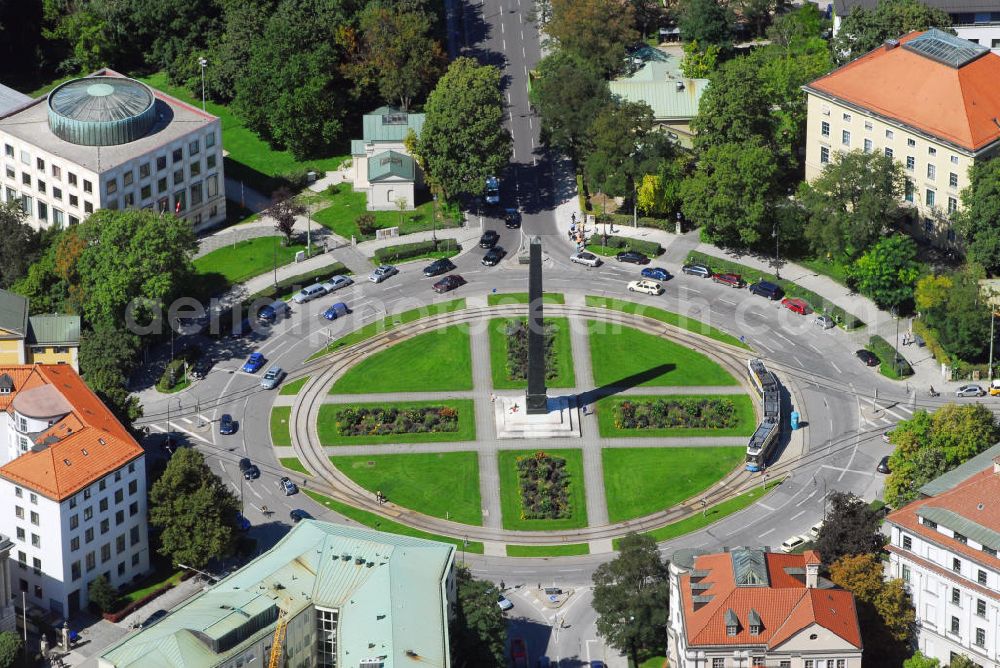 München from the bird's eye view: Blick auf den Karolinenplatz in München. Der Karolinenplatz ist ein öffentlicher Platz im Münchner Stadtteil Maxvorstadt. Er ist der erste Platz in München, der das Motiv des Strahlenplatzes aufgreift. Gleichzeitig will der Karolinenplatz die Entwicklung der besonderen Beziehung zwischen Bayern und Frankreich im 19. Jh. symbolisieren. Die Geschichte des Karolinenplatzes ist eng mit der Brienner Straße verknüpft. Bereits in einem städtebaulichen Wettbewerb von 1807 für die Maxvorstadt, aus dem der Plan für ein hippodamisch organisiertes Viertel hervorgeht, war ein Platz am alten wittelsbachischen Fürstenweg von der Münchner Residenz zum Schloss Nymphenburg, der heutigen Brienner Straße, an der Stelle des heutigen Karolinenplatz vorgesehen. Die Geschichte Bayerns ist eng mit der Frankreichs verknüpft. Brienner Straße und Barer Straße sind nach Orten von Schlachten des Deutsch-Französischer Krieges 1870/71 benannt, an deren siegreichem Ausgang bayerische Truppen besonderen Anteil hatten. Auf dem Schnittpunkt der beiden Straßen der „großen Siege“ steht der von Klenze 1833 errichtete, 29 m hohe Obelisk, der an die 30.000 bayerischen Gefallenen des Rußlandfeldzuges Napoléons erinnert. Somit sind Anfang und Ende dieser besonderen Beziehung zwischen München und Napoléon und seinen Nachfolgern im Schnittpunkt vereint. Im Zweiten Weltkrieg schwer beschädigt, ist der Karolinenplatz heute weitgehend von Neubauten geprägt, die den klassizistischen Eindruck nicht wiederherstellen.