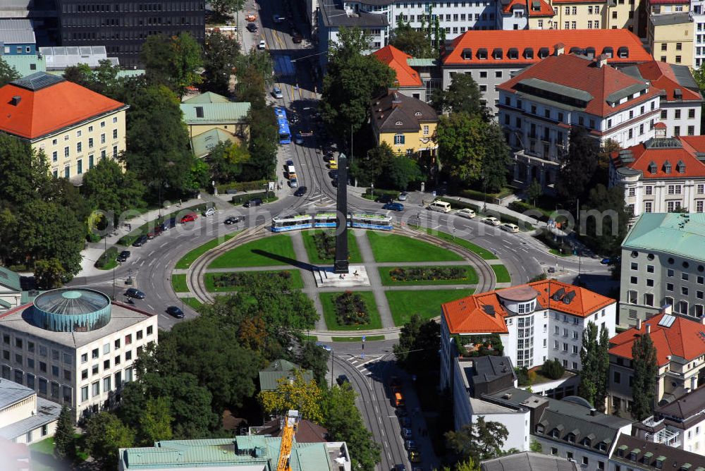 München from the bird's eye view: Blick auf den Karolinenplatz in München. Der Karolinenplatz ist ein öffentlicher Platz im Münchner Stadtteil Maxvorstadt. Er ist der erste Platz in München, der das Motiv des Strahlenplatzes aufgreift. Gleichzeitig will der Karolinenplatz die Entwicklung der besonderen Beziehung zwischen Bayern und Frankreich im 19. Jh. symbolisieren. Die Geschichte des Karolinenplatzes ist eng mit der Brienner Straße verknüpft. Bereits in einem städtebaulichen Wettbewerb von 1807 für die Maxvorstadt, aus dem der Plan für ein hippodamisch organisiertes Viertel hervorgeht, war ein Platz am alten wittelsbachischen Fürstenweg von der Münchner Residenz zum Schloss Nymphenburg, der heutigen Brienner Straße, an der Stelle des heutigen Karolinenplatz vorgesehen. Die Geschichte Bayerns ist eng mit der Frankreichs verknüpft. Brienner Straße und Barer Straße sind nach Orten von Schlachten des Deutsch-Französischer Krieges 1870/71 benannt, an deren siegreichem Ausgang bayerische Truppen besonderen Anteil hatten. Auf dem Schnittpunkt der beiden Straßen der „großen Siege“ steht der von Klenze 1833 errichtete, 29 m hohe Obelisk, der an die 30.000 bayerischen Gefallenen des Rußlandfeldzuges Napoléons erinnert. Somit sind Anfang und Ende dieser besonderen Beziehung zwischen München und Napoléon und seinen Nachfolgern im Schnittpunkt vereint. Im Zweiten Weltkrieg schwer beschädigt, ist der Karolinenplatz heute weitgehend von Neubauten geprägt, die den klassizistischen Eindruck nicht wiederherstellen.