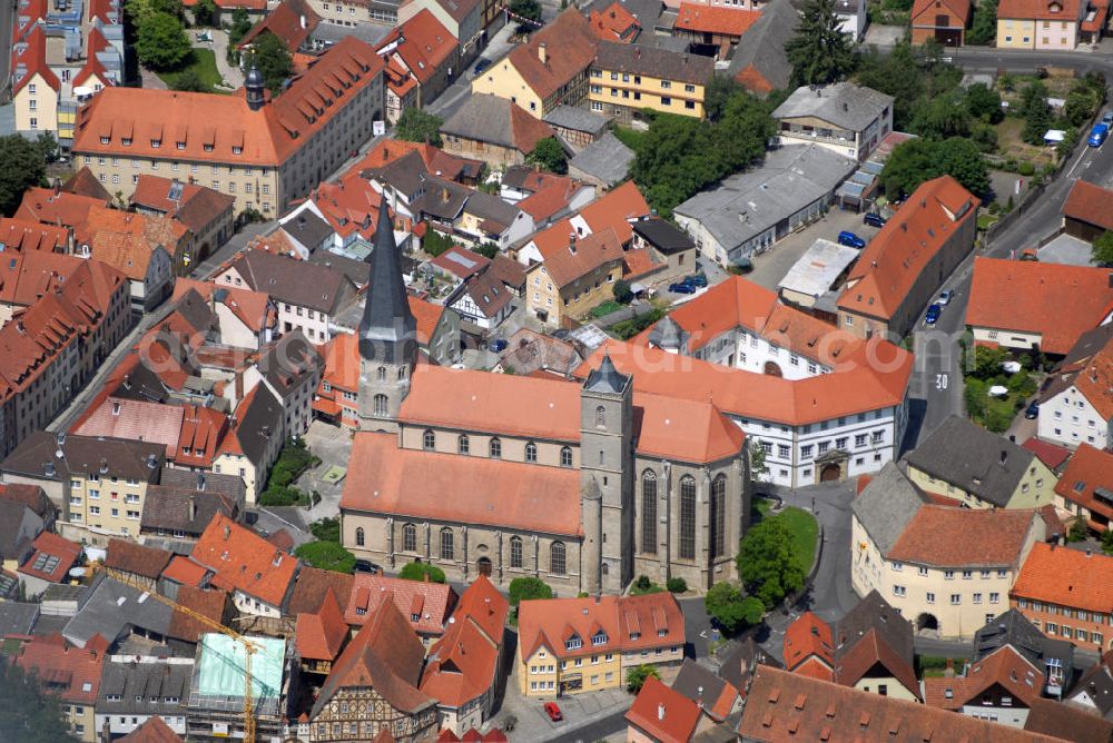 Aerial photograph Münnerstadt - Blick auf die Stadtpfarrkirche Münnerstadt. Die Katholische Stadtpfarrkirche St. Maria Magdalena entstand um 1230 im spätromanischen Stil dreischiffig. Zu Beginn des 15. Jh. leiteten die Ordensritter den Umbau im gotichen Stil ein. Heute bekannt für den 1428 bis 1446 errichteten Hochaltar mit Glasmalereien und dem Magdalenaltar mit Riemenschneiderskulpturen von 1492. 1610 lässt Fürstbischof Julius Echter das Haupt- und die beiden Seitenschiffe zu einer mächtigen Renaissancehalle umbauen. Historisch besonders Wertvoll sind die vier 1503 von Veit Stoß geschaffenen Bildtalfeln der Klianslegende und die gotische Tafel Marientod sowie die 18 Zunftstangen (1680-1830) im Hochchor.