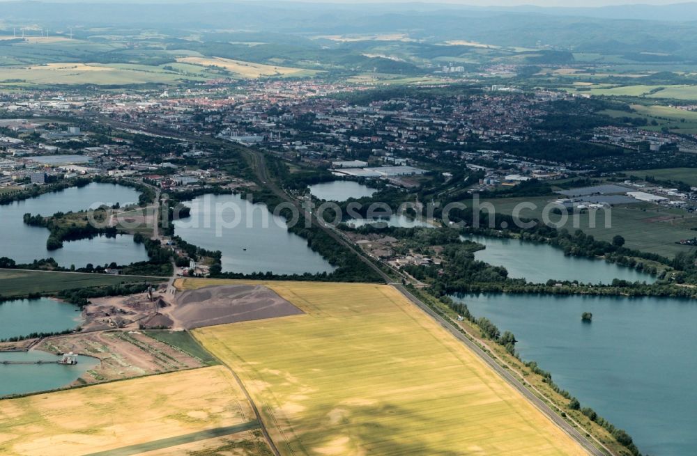 Nordhausen from the bird's eye view: On the southeast outskirts of Nordhausen in Thuringia in the district Sundhausen there are several lakes that are the result of gravel extraction. In recent years, on the shores of the lakes big industrial companies with different branches have developed