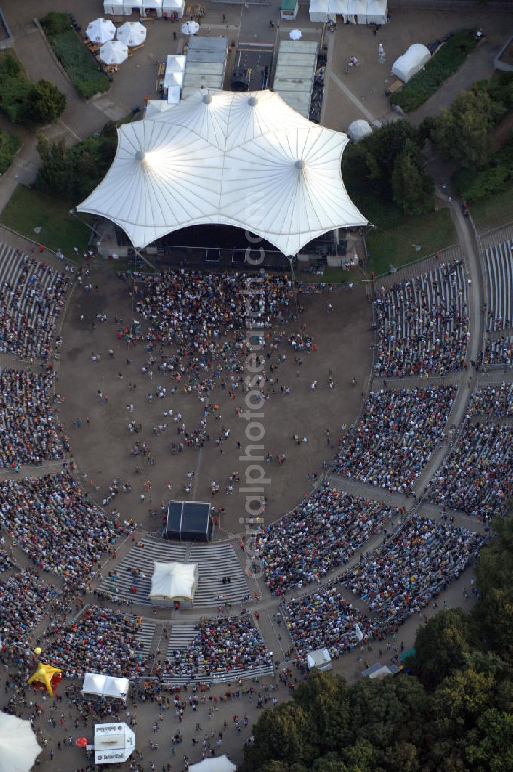 Berlin from the bird's eye view: Blick auf die Kindl-Bühne (auch Parkbühne Wuhlheide genannt) eine Viertelstunde nach Einlassbeginn zum Abschluss-Konzert von Peter Fox featuring Cold Steel. Einlass war ab 17.00 Uhr, Konzertbeginn um 19.30 Uhr. Einige Konzertbesucher haben es sich während der langen Wartezeit auf Matten bequem gemacht. Das Konzert war ausverkauft. Kontakt Kindl-Bühne Wuhlheide: Tel. +49(0)30 8575810, Email: info@wuhlheide.de