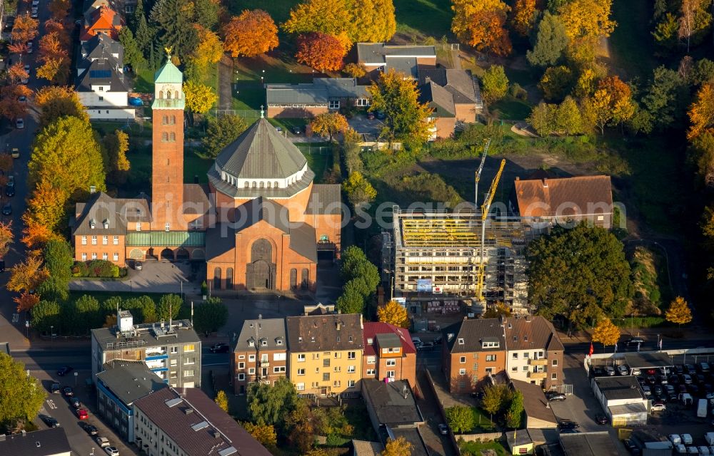 Gladbeck from the bird's eye view: Church building of the catholic Heilig-Kreuz church in the autumnal Gladbeck in the state of North Rhine-Westphalia. The construction site of a medical centre is located next to it