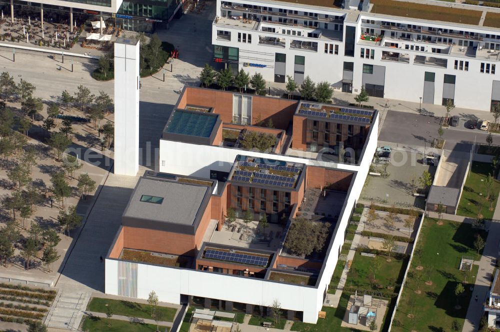 Aerial photograph München - Das Kirchenzentrum Riem ist die räumliche wie auch geistige Mitte der 556 Hektar großen Messestadt Riem auf dem ehemaligen Flughafenbgelände ist das Kirchenzentrum der beiden großen christlichen Konfessionen am Platz der Menschenrechte. Die Pfarrerswohnung, die sich mit insgesamt fünf Zimmern auf zwei Ebenen über den Gemeinderäumen für Mutter und Kind erstreckt, orientiert sich nicht nur nach Süden auf einen großen Innenhof mit Bäumen. Vom ersten Obergeschoss des Pfarrhauses führt auch ein langer Holzsteg zu zwei Dachterrassen, die sich für Wolfgang Gerbere wie für kirchliche Zwecke nutzen lassen. Allein schon dieser Bereich des Kirchenzentrums vermittelt die städtebauliche Grundidee von Architekt Florian Nagler: Die ganze Anlage richtet sich nach innen auf vier unterschiedlich dimensionierte Höfe, die von hohen Wänden mit einem präzisen Fugenbild geschützt sind. Konsequenterweise hat Nagler mehrere Flachdächer für Veranstaltungen im Freien aktiviert.