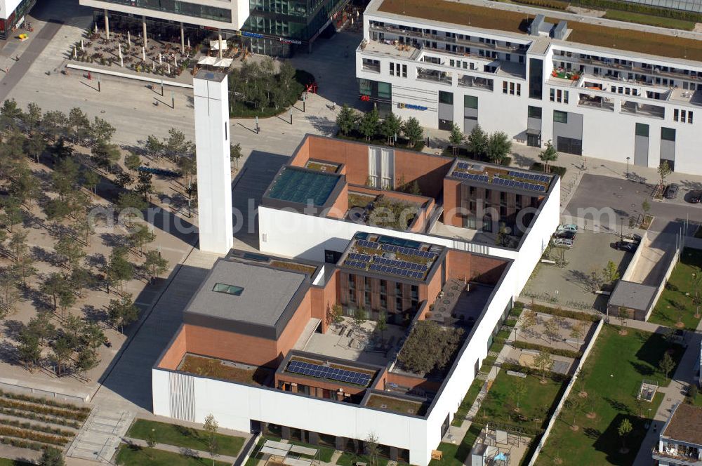 München from above - Das Kirchenzentrum Riem ist die räumliche wie auch geistige Mitte der 556 Hektar großen Messestadt Riem auf dem ehemaligen Flughafenbgelände ist das Kirchenzentrum der beiden großen christlichen Konfessionen am Platz der Menschenrechte. Die Pfarrerswohnung, die sich mit insgesamt fünf Zimmern auf zwei Ebenen über den Gemeinderäumen für Mutter und Kind erstreckt, orientiert sich nicht nur nach Süden auf einen großen Innenhof mit Bäumen. Vom ersten Obergeschoss des Pfarrhauses führt auch ein langer Holzsteg zu zwei Dachterrassen, die sich für Wolfgang Gerbere wie für kirchliche Zwecke nutzen lassen. Allein schon dieser Bereich des Kirchenzentrums vermittelt die städtebauliche Grundidee von Architekt Florian Nagler: Die ganze Anlage richtet sich nach innen auf vier unterschiedlich dimensionierte Höfe, die von hohen Wänden mit einem präzisen Fugenbild geschützt sind. Konsequenterweise hat Nagler mehrere Flachdächer für Veranstaltungen im Freien aktiviert.