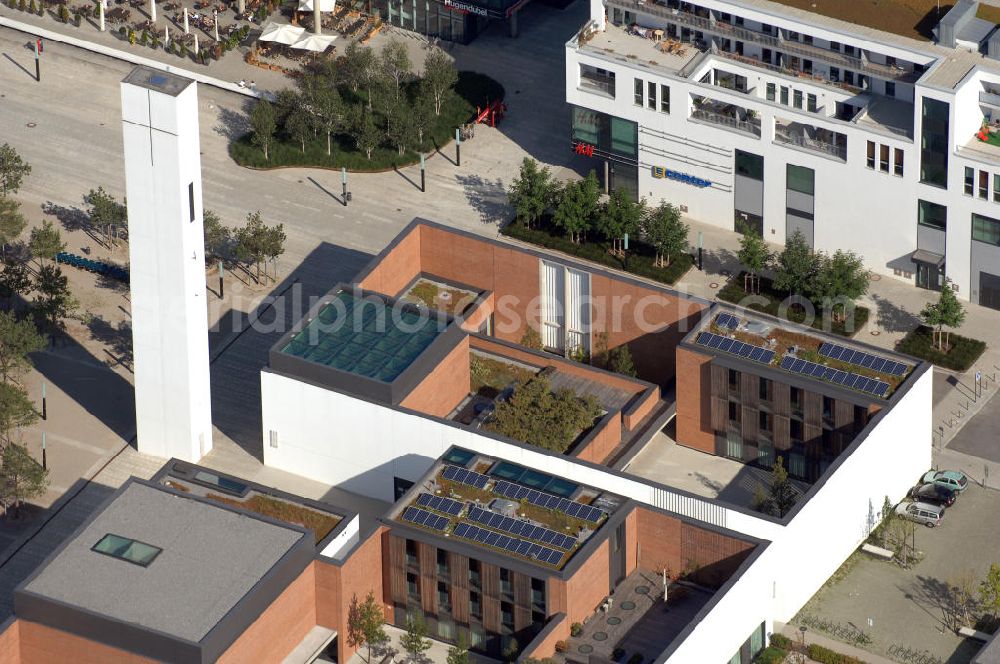 München from the bird's eye view: Das Kirchenzentrum Riem ist die räumliche wie auch geistige Mitte der 556 Hektar großen Messestadt Riem auf dem ehemaligen Flughafenbgelände ist das Kirchenzentrum der beiden großen christlichen Konfessionen am Platz der Menschenrechte. Die Pfarrerswohnung, die sich mit insgesamt fünf Zimmern auf zwei Ebenen über den Gemeinderäumen für Mutter und Kind erstreckt, orientiert sich nicht nur nach Süden auf einen großen Innenhof mit Bäumen. Vom ersten Obergeschoss des Pfarrhauses führt auch ein langer Holzsteg zu zwei Dachterrassen, die sich für Wolfgang Gerbere wie für kirchliche Zwecke nutzen lassen. Allein schon dieser Bereich des Kirchenzentrums vermittelt die städtebauliche Grundidee von Architekt Florian Nagler: Die ganze Anlage richtet sich nach innen auf vier unterschiedlich dimensionierte Höfe, die von hohen Wänden mit einem präzisen Fugenbild geschützt sind. Konsequenterweise hat Nagler mehrere Flachdächer für Veranstaltungen im Freien aktiviert.