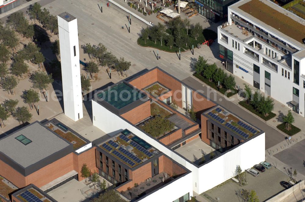 Aerial image München - Das Kirchenzentrum Riem ist die räumliche wie auch geistige Mitte der 556 Hektar großen Messestadt Riem auf dem ehemaligen Flughafenbgelände ist das Kirchenzentrum der beiden großen christlichen Konfessionen am Platz der Menschenrechte. Die Pfarrerswohnung, die sich mit insgesamt fünf Zimmern auf zwei Ebenen über den Gemeinderäumen für Mutter und Kind erstreckt, orientiert sich nicht nur nach Süden auf einen großen Innenhof mit Bäumen. Vom ersten Obergeschoss des Pfarrhauses führt auch ein langer Holzsteg zu zwei Dachterrassen, die sich für Wolfgang Gerbere wie für kirchliche Zwecke nutzen lassen. Allein schon dieser Bereich des Kirchenzentrums vermittelt die städtebauliche Grundidee von Architekt Florian Nagler: Die ganze Anlage richtet sich nach innen auf vier unterschiedlich dimensionierte Höfe, die von hohen Wänden mit einem präzisen Fugenbild geschützt sind. Konsequenterweise hat Nagler mehrere Flachdächer für Veranstaltungen im Freien aktiviert.