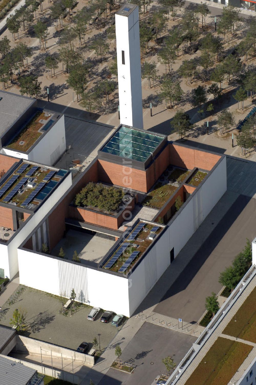 München from the bird's eye view: Das Kirchenzentrum Riem ist die räumliche wie auch geistige Mitte der 556 Hektar großen Messestadt Riem auf dem ehemaligen Flughafenbgelände ist das Kirchenzentrum der beiden großen christlichen Konfessionen am Platz der Menschenrechte. Die Pfarrerswohnung, die sich mit insgesamt fünf Zimmern auf zwei Ebenen über den Gemeinderäumen für Mutter und Kind erstreckt, orientiert sich nicht nur nach Süden auf einen großen Innenhof mit Bäumen. Vom ersten Obergeschoss des Pfarrhauses führt auch ein langer Holzsteg zu zwei Dachterrassen, die sich für Wolfgang Gerbere wie für kirchliche Zwecke nutzen lassen. Allein schon dieser Bereich des Kirchenzentrums vermittelt die städtebauliche Grundidee von Architekt Florian Nagler: Die ganze Anlage richtet sich nach innen auf vier unterschiedlich dimensionierte Höfe, die von hohen Wänden mit einem präzisen Fugenbild geschützt sind. Konsequenterweise hat Nagler mehrere Flachdächer für Veranstaltungen im Freien aktiviert.