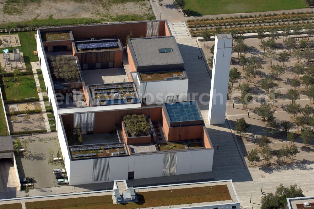 München from above - Das Kirchenzentrum Riem ist die räumliche wie auch geistige Mitte der 556 Hektar großen Messestadt Riem auf dem ehemaligen Flughafenbgelände ist das Kirchenzentrum der beiden großen christlichen Konfessionen am Platz der Menschenrechte. Die Pfarrerswohnung, die sich mit insgesamt fünf Zimmern auf zwei Ebenen über den Gemeinderäumen für Mutter und Kind erstreckt, orientiert sich nicht nur nach Süden auf einen großen Innenhof mit Bäumen. Vom ersten Obergeschoss des Pfarrhauses führt auch ein langer Holzsteg zu zwei Dachterrassen, die sich für Wolfgang Gerbere wie für kirchliche Zwecke nutzen lassen. Allein schon dieser Bereich des Kirchenzentrums vermittelt die städtebauliche Grundidee von Architekt Florian Nagler: Die ganze Anlage richtet sich nach innen auf vier unterschiedlich dimensionierte Höfe, die von hohen Wänden mit einem präzisen Fugenbild geschützt sind. Konsequenterweise hat Nagler mehrere Flachdächer für Veranstaltungen im Freien aktiviert.