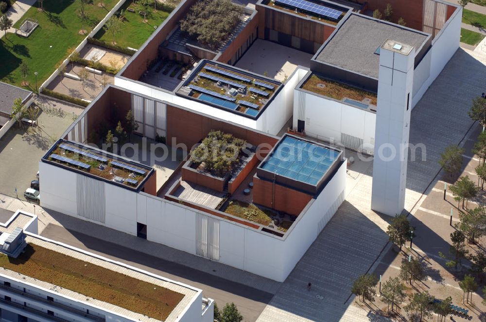 München from the bird's eye view: Das Kirchenzentrum Riem ist die räumliche wie auch geistige Mitte der 556 Hektar großen Messestadt Riem auf dem ehemaligen Flughafenbgelände ist das Kirchenzentrum der beiden großen christlichen Konfessionen am Platz der Menschenrechte. Die Pfarrerswohnung, die sich mit insgesamt fünf Zimmern auf zwei Ebenen über den Gemeinderäumen für Mutter und Kind erstreckt, orientiert sich nicht nur nach Süden auf einen großen Innenhof mit Bäumen. Vom ersten Obergeschoss des Pfarrhauses führt auch ein langer Holzsteg zu zwei Dachterrassen, die sich für Wolfgang Gerbere wie für kirchliche Zwecke nutzen lassen. Allein schon dieser Bereich des Kirchenzentrums vermittelt die städtebauliche Grundidee von Architekt Florian Nagler: Die ganze Anlage richtet sich nach innen auf vier unterschiedlich dimensionierte Höfe, die von hohen Wänden mit einem präzisen Fugenbild geschützt sind. Konsequenterweise hat Nagler mehrere Flachdächer für Veranstaltungen im Freien aktiviert.