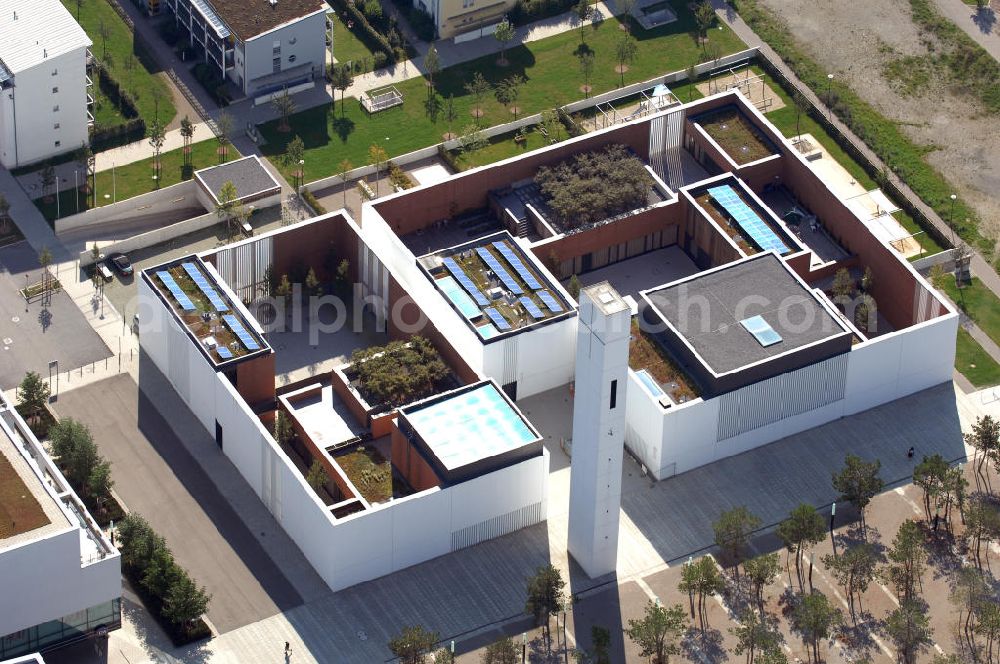 Aerial photograph München - Das Kirchenzentrum Riem ist die räumliche wie auch geistige Mitte der 556 Hektar großen Messestadt Riem auf dem ehemaligen Flughafenbgelände ist das Kirchenzentrum der beiden großen christlichen Konfessionen am Platz der Menschenrechte. Die Pfarrerswohnung, die sich mit insgesamt fünf Zimmern auf zwei Ebenen über den Gemeinderäumen für Mutter und Kind erstreckt, orientiert sich nicht nur nach Süden auf einen großen Innenhof mit Bäumen. Vom ersten Obergeschoss des Pfarrhauses führt auch ein langer Holzsteg zu zwei Dachterrassen, die sich für Wolfgang Gerbere wie für kirchliche Zwecke nutzen lassen. Allein schon dieser Bereich des Kirchenzentrums vermittelt die städtebauliche Grundidee von Architekt Florian Nagler: Die ganze Anlage richtet sich nach innen auf vier unterschiedlich dimensionierte Höfe, die von hohen Wänden mit einem präzisen Fugenbild geschützt sind. Konsequenterweise hat Nagler mehrere Flachdächer für Veranstaltungen im Freien aktiviert.