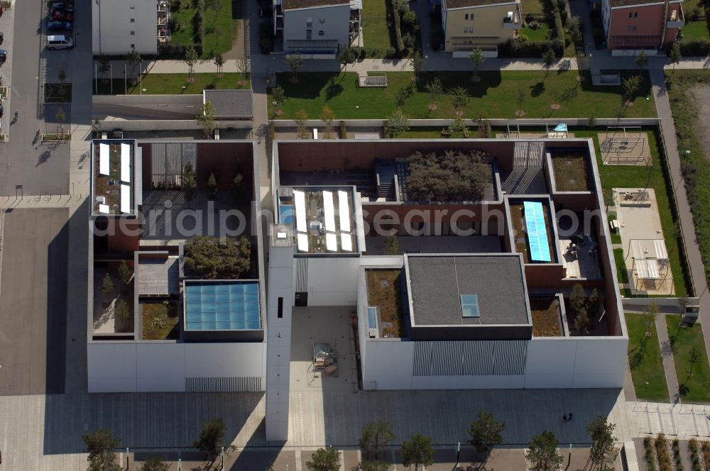 München from above - Das Kirchenzentrum Riem ist die räumliche wie auch geistige Mitte der 556 Hektar großen Messestadt Riem auf dem ehemaligen Flughafenbgelände ist das Kirchenzentrum der beiden großen christlichen Konfessionen am Platz der Menschenrechte. Die Pfarrerswohnung, die sich mit insgesamt fünf Zimmern auf zwei Ebenen über den Gemeinderäumen für Mutter und Kind erstreckt, orientiert sich nicht nur nach Süden auf einen großen Innenhof mit Bäumen. Vom ersten Obergeschoss des Pfarrhauses führt auch ein langer Holzsteg zu zwei Dachterrassen, die sich für Wolfgang Gerbere wie für kirchliche Zwecke nutzen lassen. Allein schon dieser Bereich des Kirchenzentrums vermittelt die städtebauliche Grundidee von Architekt Florian Nagler: Die ganze Anlage richtet sich nach innen auf vier unterschiedlich dimensionierte Höfe, die von hohen Wänden mit einem präzisen Fugenbild geschützt sind. Konsequenterweise hat Nagler mehrere Flachdächer für Veranstaltungen im Freien aktiviert.