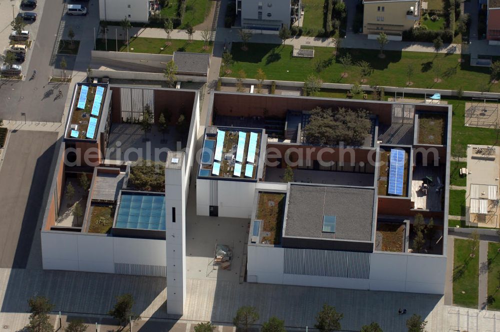 München from the bird's eye view: Das Kirchenzentrum Riem ist die räumliche wie auch geistige Mitte der 556 Hektar großen Messestadt Riem auf dem ehemaligen Flughafenbgelände ist das Kirchenzentrum der beiden großen christlichen Konfessionen am Platz der Menschenrechte. Die Pfarrerswohnung, die sich mit insgesamt fünf Zimmern auf zwei Ebenen über den Gemeinderäumen für Mutter und Kind erstreckt, orientiert sich nicht nur nach Süden auf einen großen Innenhof mit Bäumen. Vom ersten Obergeschoss des Pfarrhauses führt auch ein langer Holzsteg zu zwei Dachterrassen, die sich für Wolfgang Gerbere wie für kirchliche Zwecke nutzen lassen. Allein schon dieser Bereich des Kirchenzentrums vermittelt die städtebauliche Grundidee von Architekt Florian Nagler: Die ganze Anlage richtet sich nach innen auf vier unterschiedlich dimensionierte Höfe, die von hohen Wänden mit einem präzisen Fugenbild geschützt sind. Konsequenterweise hat Nagler mehrere Flachdächer für Veranstaltungen im Freien aktiviert.