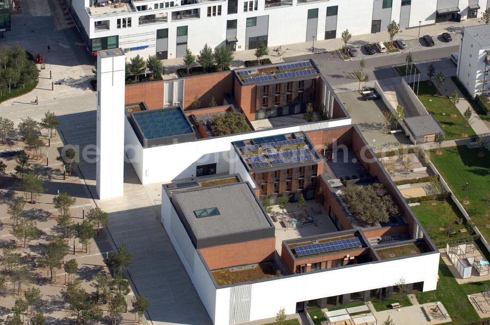 Aerial photograph München - Das Kirchenzentrum Riem ist die räumliche wie auch geistige Mitte der 556 Hektar großen Messestadt Riem auf dem ehemaligen Flughafenbgelände ist das Kirchenzentrum der beiden großen christlichen Konfessionen am Platz der Menschenrechte. Die Pfarrerswohnung, die sich mit insgesamt fünf Zimmern auf zwei Ebenen über den Gemeinderäumen für Mutter und Kind erstreckt, orientiert sich nicht nur nach Süden auf einen großen Innenhof mit Bäumen. Vom ersten Obergeschoss des Pfarrhauses führt auch ein langer Holzsteg zu zwei Dachterrassen, die sich für Wolfgang Gerbere wie für kirchliche Zwecke nutzen lassen. Allein schon dieser Bereich des Kirchenzentrums vermittelt die städtebauliche Grundidee von Architekt Florian Nagler: Die ganze Anlage richtet sich nach innen auf vier unterschiedlich dimensionierte Höfe, die von hohen Wänden mit einem präzisen Fugenbild geschützt sind. Konsequenterweise hat Nagler mehrere Flachdächer für Veranstaltungen im Freien aktiviert.