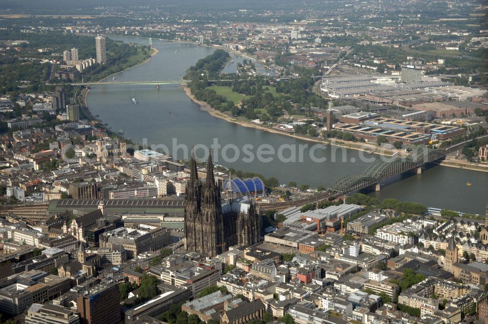 Aerial image KÖLN - Der Kölner Dom, offizieller Name Hohe Domkirche St. Peter und Maria, ist eine römisch-katholische Kirche in Köln und die Kathedrale des Erzbistums Köln.Der Kölner Dom ist mit 157 Metern Höhe nach dem Ulmer Münster die zweithöchste Kirche in Deutschland sowie die dritthöchste der Welt. Er steht an der nördlichen ehemaligen römischen Stadtgrenze in direkter Nachbarschaft des heutigen Hauptbahnhofs, der Altstadt, Hohenzollernbrücke und Museum Ludwig und ist von einer modernen Betonkonstruktion, der sogenannten Domplatte, umgeben. Vom rund 250 Meter entfernten Rhein und vom Hauptbahnhof aus ist die Lage der Kathedrale auf dem sogenannten Domhügel, rund 17 m über dem Rhein, noch zu erahnen. Der Kölner Dom ist die weltweit drittgrößte Kathedrale im gotischen Baustil (nach der Kathedrale von Sevilla und dem Mailänder Dom). Viele Kunsthistoriker sehen in ihm eine einmalige Harmonisierung sämtlicher Bauelemente und des Schmuckwerks im Stil der mittelalterlich-gotischen Architektur verwirklicht. Der Kölner Dom wurde 1996 in die Liste des Weltkulturerbes aufgenommen. Die riesige Fläche der Westfassade mitsamt den beiden Türmen von über 7.100 Quadratmetern ist bis heute nirgendwo übertroffen worden. Von 1880 bis 1884 war er das höchste Gebäude der Welt. Er ist zudem die populärste Sehenswürdigkeit Deutschlands: 2001 wurden fünf Millionen, 2004 sechs Millionen Besucher aus aller Welt gezählt.