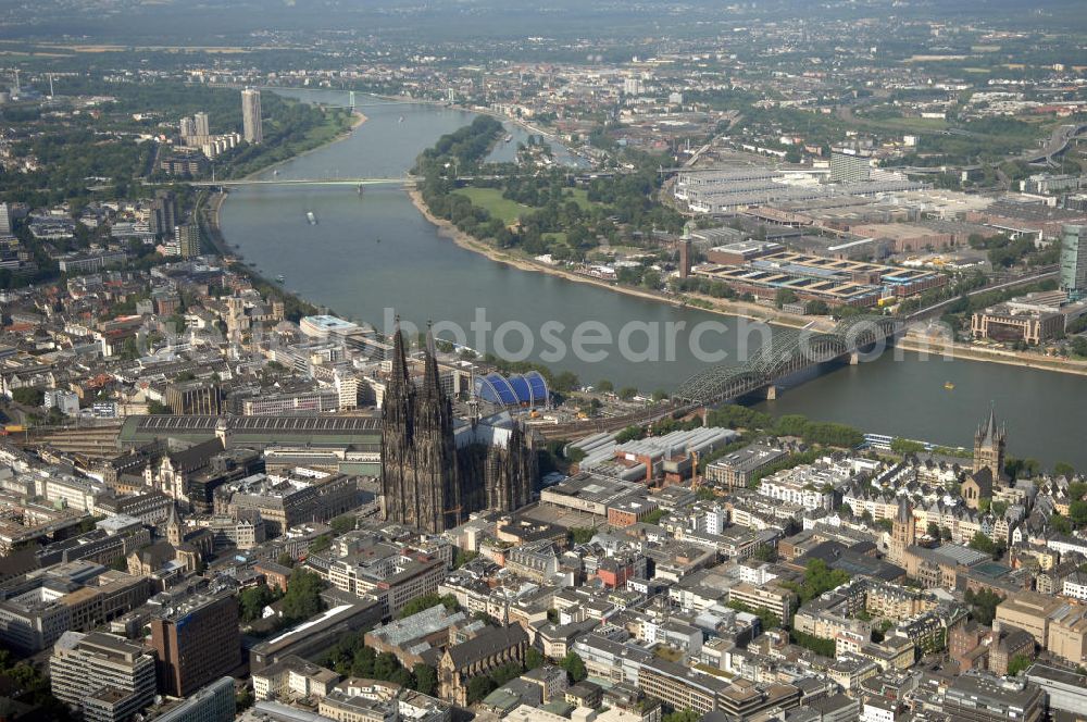 Aerial photograph KÖLN - Der Kölner Dom, offizieller Name Hohe Domkirche St. Peter und Maria, ist eine römisch-katholische Kirche in Köln und die Kathedrale des Erzbistums Köln.Der Kölner Dom ist mit 157 Metern Höhe nach dem Ulmer Münster die zweithöchste Kirche in Deutschland sowie die dritthöchste der Welt. Er steht an der nördlichen ehemaligen römischen Stadtgrenze in direkter Nachbarschaft des heutigen Hauptbahnhofs, der Altstadt, Hohenzollernbrücke und Museum Ludwig und ist von einer modernen Betonkonstruktion, der sogenannten Domplatte, umgeben. Vom rund 250 Meter entfernten Rhein und vom Hauptbahnhof aus ist die Lage der Kathedrale auf dem sogenannten Domhügel, rund 17 m über dem Rhein, noch zu erahnen. Der Kölner Dom ist die weltweit drittgrößte Kathedrale im gotischen Baustil (nach der Kathedrale von Sevilla und dem Mailänder Dom). Viele Kunsthistoriker sehen in ihm eine einmalige Harmonisierung sämtlicher Bauelemente und des Schmuckwerks im Stil der mittelalterlich-gotischen Architektur verwirklicht. Der Kölner Dom wurde 1996 in die Liste des Weltkulturerbes aufgenommen. Die riesige Fläche der Westfassade mitsamt den beiden Türmen von über 7.100 Quadratmetern ist bis heute nirgendwo übertroffen worden. Von 1880 bis 1884 war er das höchste Gebäude der Welt. Er ist zudem die populärste Sehenswürdigkeit Deutschlands: 2001 wurden fünf Millionen, 2004 sechs Millionen Besucher aus aller Welt gezählt.