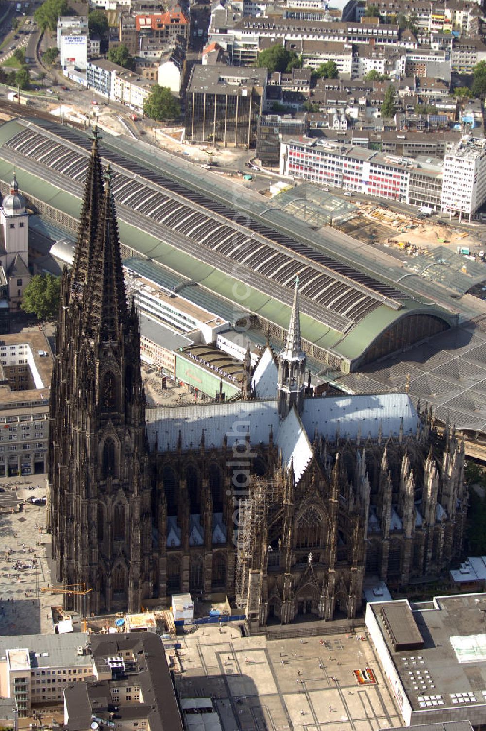 Aerial image KÖLN - Der Kölner Dom, offizieller Name Hohe Domkirche St. Peter und Maria, ist eine römisch-katholische Kirche in Köln und die Kathedrale des Erzbistums Köln.Der Kölner Dom ist mit 157 Metern Höhe nach dem Ulmer Münster die zweithöchste Kirche in Deutschland sowie die dritthöchste der Welt. Er steht an der nördlichen ehemaligen römischen Stadtgrenze in direkter Nachbarschaft des heutigen Hauptbahnhofs, der Altstadt, Hohenzollernbrücke und Museum Ludwig und ist von einer modernen Betonkonstruktion, der sogenannten Domplatte, umgeben. Vom rund 250 Meter entfernten Rhein und vom Hauptbahnhof aus ist die Lage der Kathedrale auf dem sogenannten Domhügel, rund 17 m über dem Rhein, noch zu erahnen. Der Kölner Dom ist die weltweit drittgrößte Kathedrale im gotischen Baustil (nach der Kathedrale von Sevilla und dem Mailänder Dom). Viele Kunsthistoriker sehen in ihm eine einmalige Harmonisierung sämtlicher Bauelemente und des Schmuckwerks im Stil der mittelalterlich-gotischen Architektur verwirklicht. Der Kölner Dom wurde 1996 in die Liste des Weltkulturerbes aufgenommen. Die riesige Fläche der Westfassade mitsamt den beiden Türmen von über 7.100 Quadratmetern ist bis heute nirgendwo übertroffen worden. Von 1880 bis 1884 war er das höchste Gebäude der Welt. Er ist zudem die populärste Sehenswürdigkeit Deutschlands: 2001 wurden fünf Millionen, 2004 sechs Millionen Besucher aus aller Welt gezählt.