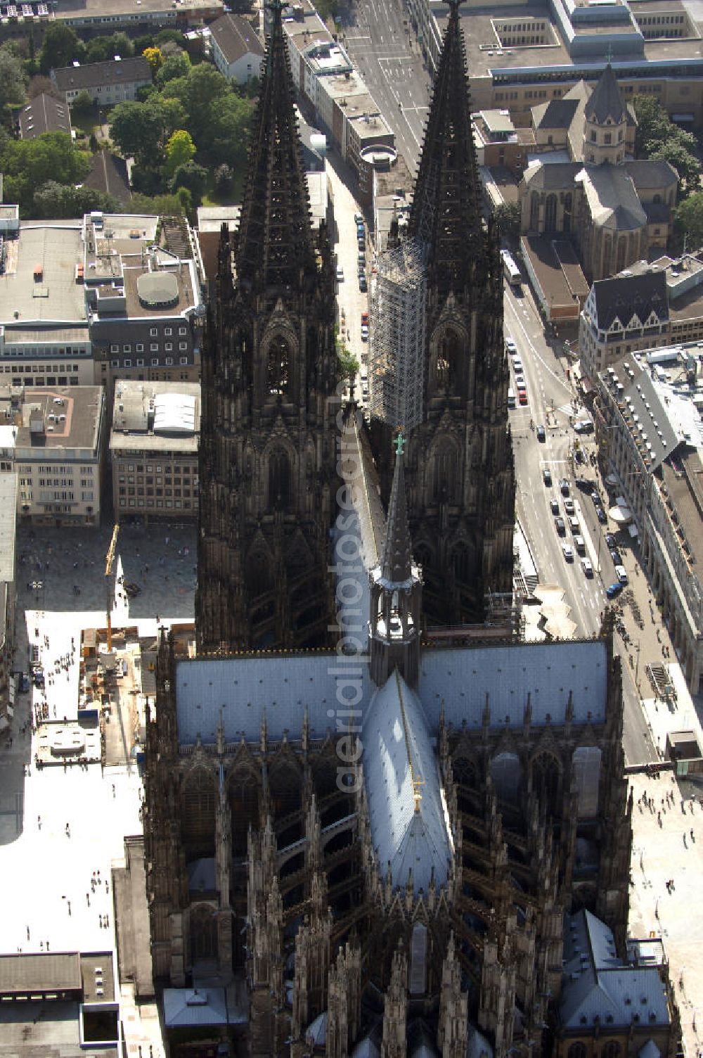 KÖLN from above - Der Kölner Dom, offizieller Name Hohe Domkirche St. Peter und Maria, ist eine römisch-katholische Kirche in Köln und die Kathedrale des Erzbistums Köln.Der Kölner Dom ist mit 157 Metern Höhe nach dem Ulmer Münster die zweithöchste Kirche in Deutschland sowie die dritthöchste der Welt. Er steht an der nördlichen ehemaligen römischen Stadtgrenze in direkter Nachbarschaft des heutigen Hauptbahnhofs, der Altstadt, Hohenzollernbrücke und Museum Ludwig und ist von einer modernen Betonkonstruktion, der sogenannten Domplatte, umgeben. Vom rund 250 Meter entfernten Rhein und vom Hauptbahnhof aus ist die Lage der Kathedrale auf dem sogenannten Domhügel, rund 17 m über dem Rhein, noch zu erahnen. Der Kölner Dom ist die weltweit drittgrößte Kathedrale im gotischen Baustil (nach der Kathedrale von Sevilla und dem Mailänder Dom). Viele Kunsthistoriker sehen in ihm eine einmalige Harmonisierung sämtlicher Bauelemente und des Schmuckwerks im Stil der mittelalterlich-gotischen Architektur verwirklicht. Der Kölner Dom wurde 1996 in die Liste des Weltkulturerbes aufgenommen. Die riesige Fläche der Westfassade mitsamt den beiden Türmen von über 7.100 Quadratmetern ist bis heute nirgendwo übertroffen worden. Von 1880 bis 1884 war er das höchste Gebäude der Welt. Er ist zudem die populärste Sehenswürdigkeit Deutschlands: 2001 wurden fünf Millionen, 2004 sechs Millionen Besucher aus aller Welt gezählt.