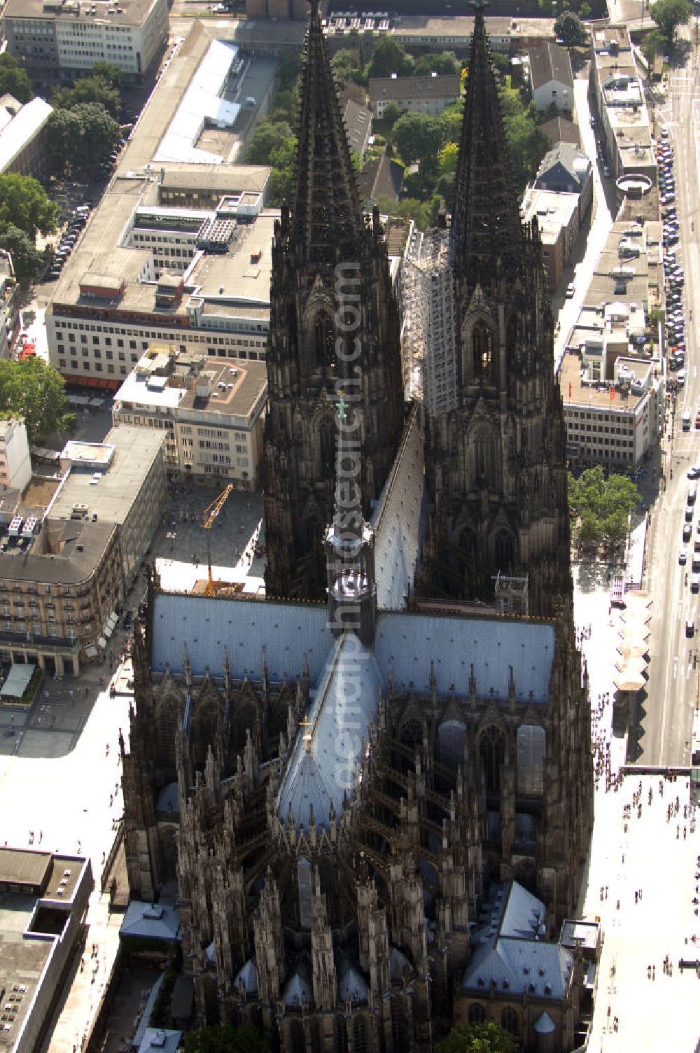 KÖLN from the bird's eye view: Der Kölner Dom, offizieller Name Hohe Domkirche St. Peter und Maria, ist eine römisch-katholische Kirche in Köln und die Kathedrale des Erzbistums Köln.Der Kölner Dom ist mit 157 Metern Höhe nach dem Ulmer Münster die zweithöchste Kirche in Deutschland sowie die dritthöchste der Welt. Er steht an der nördlichen ehemaligen römischen Stadtgrenze in direkter Nachbarschaft des heutigen Hauptbahnhofs, der Altstadt, Hohenzollernbrücke und Museum Ludwig und ist von einer modernen Betonkonstruktion, der sogenannten Domplatte, umgeben. Vom rund 250 Meter entfernten Rhein und vom Hauptbahnhof aus ist die Lage der Kathedrale auf dem sogenannten Domhügel, rund 17 m über dem Rhein, noch zu erahnen. Der Kölner Dom ist die weltweit drittgrößte Kathedrale im gotischen Baustil (nach der Kathedrale von Sevilla und dem Mailänder Dom). Viele Kunsthistoriker sehen in ihm eine einmalige Harmonisierung sämtlicher Bauelemente und des Schmuckwerks im Stil der mittelalterlich-gotischen Architektur verwirklicht. Der Kölner Dom wurde 1996 in die Liste des Weltkulturerbes aufgenommen. Die riesige Fläche der Westfassade mitsamt den beiden Türmen von über 7.100 Quadratmetern ist bis heute nirgendwo übertroffen worden. Von 1880 bis 1884 war er das höchste Gebäude der Welt. Er ist zudem die populärste Sehenswürdigkeit Deutschlands: 2001 wurden fünf Millionen, 2004 sechs Millionen Besucher aus aller Welt gezählt.