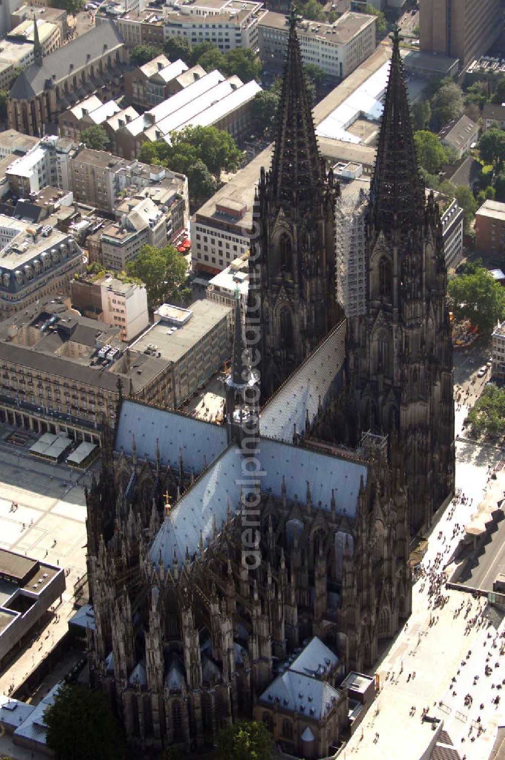 Aerial image KÖLN - Der Kölner Dom, offizieller Name Hohe Domkirche St. Peter und Maria, ist eine römisch-katholische Kirche in Köln und die Kathedrale des Erzbistums Köln.Der Kölner Dom ist mit 157 Metern Höhe nach dem Ulmer Münster die zweithöchste Kirche in Deutschland sowie die dritthöchste der Welt. Er steht an der nördlichen ehemaligen römischen Stadtgrenze in direkter Nachbarschaft des heutigen Hauptbahnhofs, der Altstadt, Hohenzollernbrücke und Museum Ludwig und ist von einer modernen Betonkonstruktion, der sogenannten Domplatte, umgeben. Vom rund 250 Meter entfernten Rhein und vom Hauptbahnhof aus ist die Lage der Kathedrale auf dem sogenannten Domhügel, rund 17 m über dem Rhein, noch zu erahnen. Der Kölner Dom ist die weltweit drittgrößte Kathedrale im gotischen Baustil (nach der Kathedrale von Sevilla und dem Mailänder Dom). Viele Kunsthistoriker sehen in ihm eine einmalige Harmonisierung sämtlicher Bauelemente und des Schmuckwerks im Stil der mittelalterlich-gotischen Architektur verwirklicht. Der Kölner Dom wurde 1996 in die Liste des Weltkulturerbes aufgenommen. Die riesige Fläche der Westfassade mitsamt den beiden Türmen von über 7.100 Quadratmetern ist bis heute nirgendwo übertroffen worden. Von 1880 bis 1884 war er das höchste Gebäude der Welt. Er ist zudem die populärste Sehenswürdigkeit Deutschlands: 2001 wurden fünf Millionen, 2004 sechs Millionen Besucher aus aller Welt gezählt.