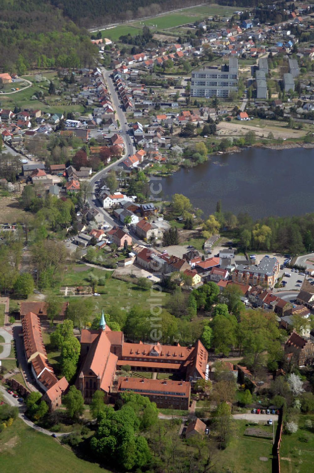 LEHNIN from the bird's eye view: Das Kloster Lehnin in der gleichnamigen Gemeinde südwestlich von Potsdam ist eine ehemalige Zisterzienserabtei. 1180 gegründet und im Zuge der Reformation 1542 säkularisiert, beherbergt es seit 1911 das Luise-Henrietten-Stift. Das Kloster liegt im Zentrum der Hochfläche Zauche in wald- und wasserreicher Umgebung rund 700 Meter vom Klostersee entfernt. Das Kloster spielte im Hochmittelalter eine wichtige Rolle beim Landesausbau der jungen Mark Brandenburg unter deren ersten Markgrafen aus dem Haus der Askanier. Neben seiner historischen kommt dem Kloster auch eine große kulturelle Bedeutung zu: Seine Kirche zählt zu den wichtigsten romanisch-gotischen Backsteinbauten in Brandenburg. Deren Rekonstruktion in den Jahren von 1871 bis 1877 gilt als frühe Glanzleistung der modernen Denkmalpflege. Das heutige Lehniner Stift sieht sich mit seinen pflegerischen, medizinischen und ausbildenden diakonischen Einrichtungen in der klösterlichen Tradition und versteht sich als Schaufenster der Evangelischen Kirche.