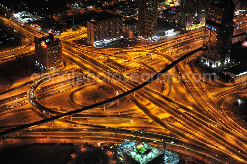 DUBAI / DUBAYY from the bird's eye view: Nachtluftbild vom Kreisverkehr an der D71 Financial Centre Road und der E 11 Sheikh Zayed Road. Moderne, teilweise sechsspurig beleuchtet ausgebaute Autobahnen und Schnellstraßen kennzeichnen die Infrastruktur aller Städte der Emirate. First Interchange on Sheikh Zayed Road, also known as Defense Roundabout.