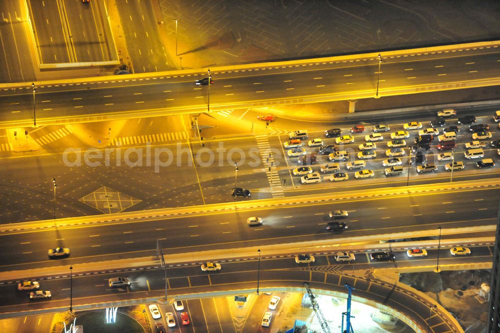 DUBAI / DUBAYY from the bird's eye view: Nachtluftbild vom Kreisverkehr an der D71 Financial Centre Road und der E 11 Sheikh Zayed Road. Moderne, teilweise sechsspurig beleuchtet ausgebaute Autobahnen und Schnellstraßen kennzeichnen die Infrastruktur aller Städte der Emirate. First Interchange on Sheikh Zayed Road, also known as Defense Roundabout.