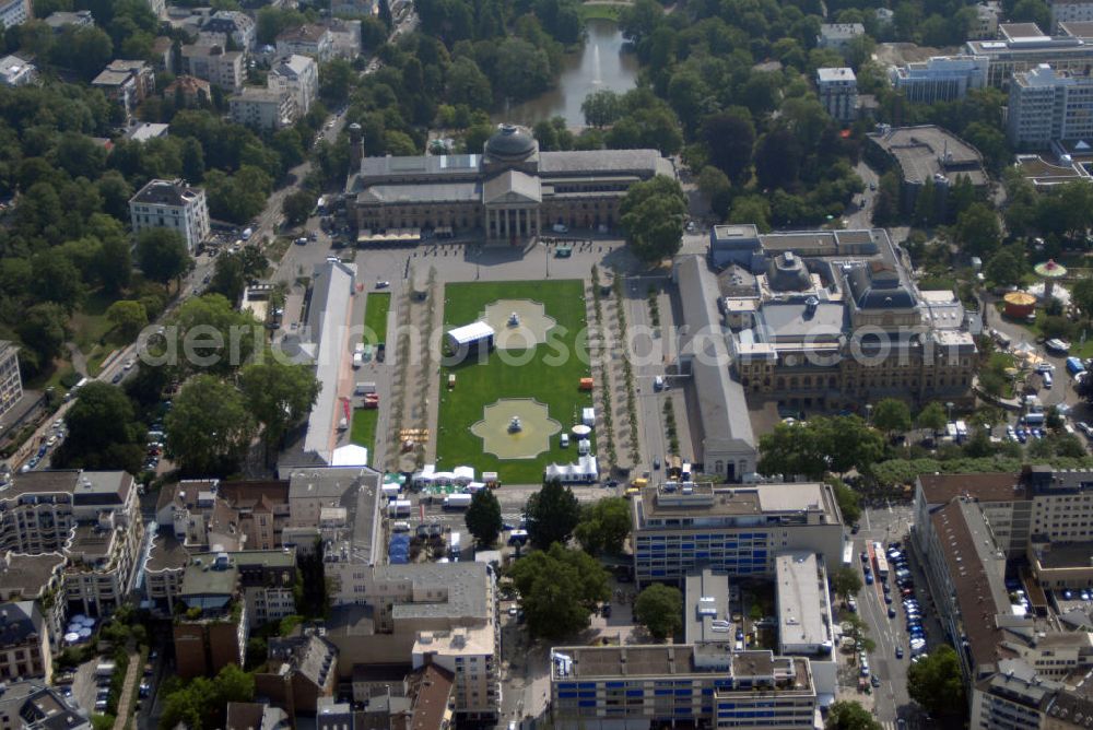 Wiesbaden from above - Blick auf den Kurhausplatz Bowling Green in Wiesbaden. Das Bowling Green ist eine Grünanlage in der hessischen Landeshauptstadt Wiesbaden. Die Bezeichnung Bowling Green stammt angeblich von englischen Kurgästen aus dem 19. Jh., die den Rasen mit einem englischen Ballspielplatz verglichen (Bowle). Das Bowling Green wird wegen seiner beeindruckenden Kulisse oft für Open-Air-Veranstaltungen genutzt. So fanden hier beispielsweise schon des Öfteren Konzerte statt. An den Platz grenzen: Das Kurhaus Wiesbaden und das Hessische Staatstheater Wiesbaden so unter an derem die Spielbank Wiesbaden im Kurhaus.