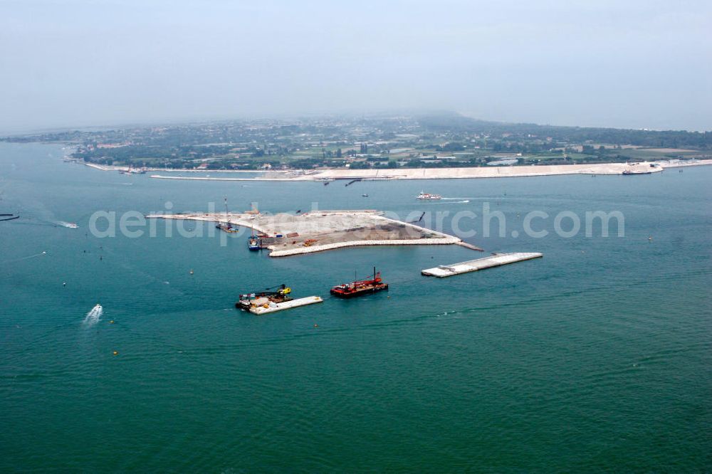 Aerial photograph Venedig - Blick auf die Baustelle des Projekts M.O.S.E. bei Punta Sabbioni in Venedig. Die Abkürzung M.O.S.E. steht für modulo sperimentale eletromeccanico und bezeichnet ein bewegliches Flutschutzwehr. Das Sperrwerk soll besonders die historische Altstadt Venedigs vor Überflutungen schützen. Die Bauarbeiten begannen 2003. Umgesetzt wird das Projekt von der Firmengemeinschaft Consorzio Venezia Nuova, einem Zusammenschluss der 30 größten Baufirmen Italiens. View to the building area of the project M.O.S.E. near Punta Sabbioni in Venedig. The abbrevation M.O.S.E. stands for modulo sperimentale eletromeccanico and describes an moveable flood protection weir. The barrage should protect espacially the historic city of Venedig from flood. the construction work started in 2003. The project is realised from the company group Consorzio Venezia Nuova, wich is an union of the 30 largest building companys in italy.