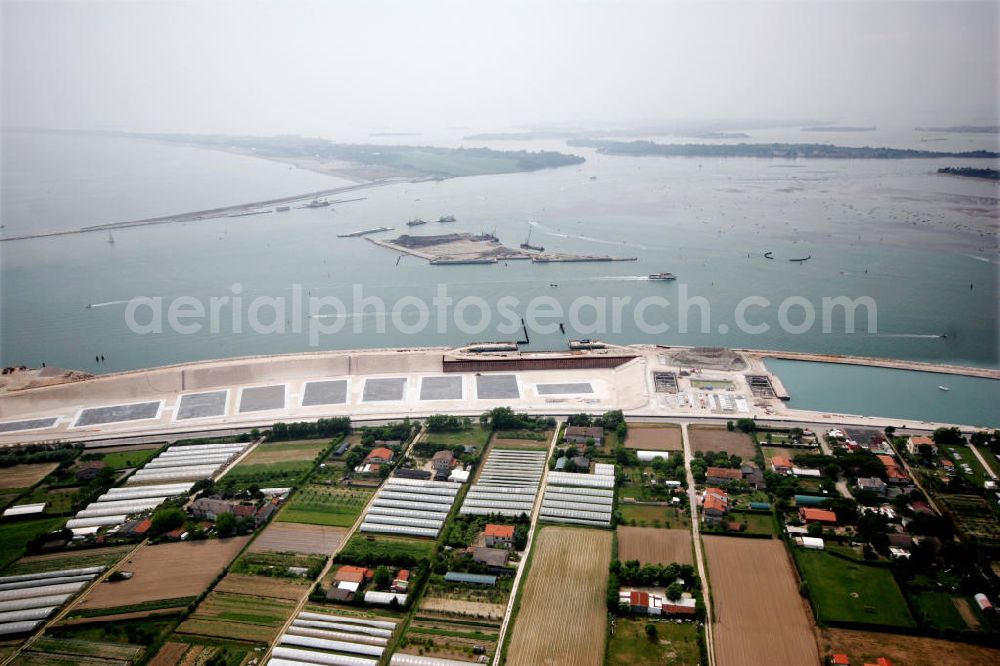 Venedig from the bird's eye view: Blick auf die Baustelle des Projekts M.O.S.E. bei Punta Sabbioni in Venedig. Die Abkürzung M.O.S.E. steht für modulo sperimentale eletromeccanico und bezeichnet ein bewegliches Flutschutzwehr. Das Sperrwerk soll besonders die historische Altstadt Venedigs vor Überflutungen schützen. Die Bauarbeiten begannen 2003. Umgesetzt wird das Projekt von der Firmengemeinschaft Consorzio Venezia Nuova, einem Zusammenschluss der 30 größten Baufirmen Italiens. View to the building area of the project M.O.S.E. near Punta Sabbioni in Venedig. The abbrevation M.O.S.E. stands for modulo sperimentale eletromeccanico and describes an moveable flood protection weir. The barrage should protect espacially the historic city of Venedig from flood. the construction work started in 2003. The project is realised from the company group Consorzio Venezia Nuova, wich is an union of the 30 largest building companys in italy.