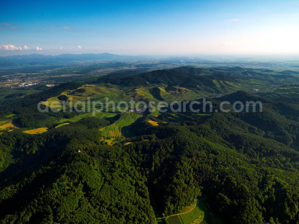 SCHELINGEN from the bird's eye view: Blick auf die Landschaften des Kaiserstuhl s, einem hohes Mittelgebirge vulkanischen Ursprungs in den Landkreisen Emmendingen und Breisgau-Hochschwarzwald im Südwesten von Baden-Württemberg. Naturräumlich wird er zum Oberrheinischen Tiefland gezählt. Seinen Namen hat der Kaiserstuhl vermutlich von König Otto III., der bei Sasbach am 22. Dezember 994 einen Gerichtstag abhielt. Nach diesem Gerichtstag wurde das ganze Gebirge als „Königsstuhl“ bezeichnet. Nachdem Otto III. im Mai 996 zum Kaiser gekrönt war, wurde aus dem „ Königsstuhl “ der „ Kaiserstuhl “. Landscapes of the Kaiserstuhl s, a high mountain range in southwestern Baden-Wuerttemberg.