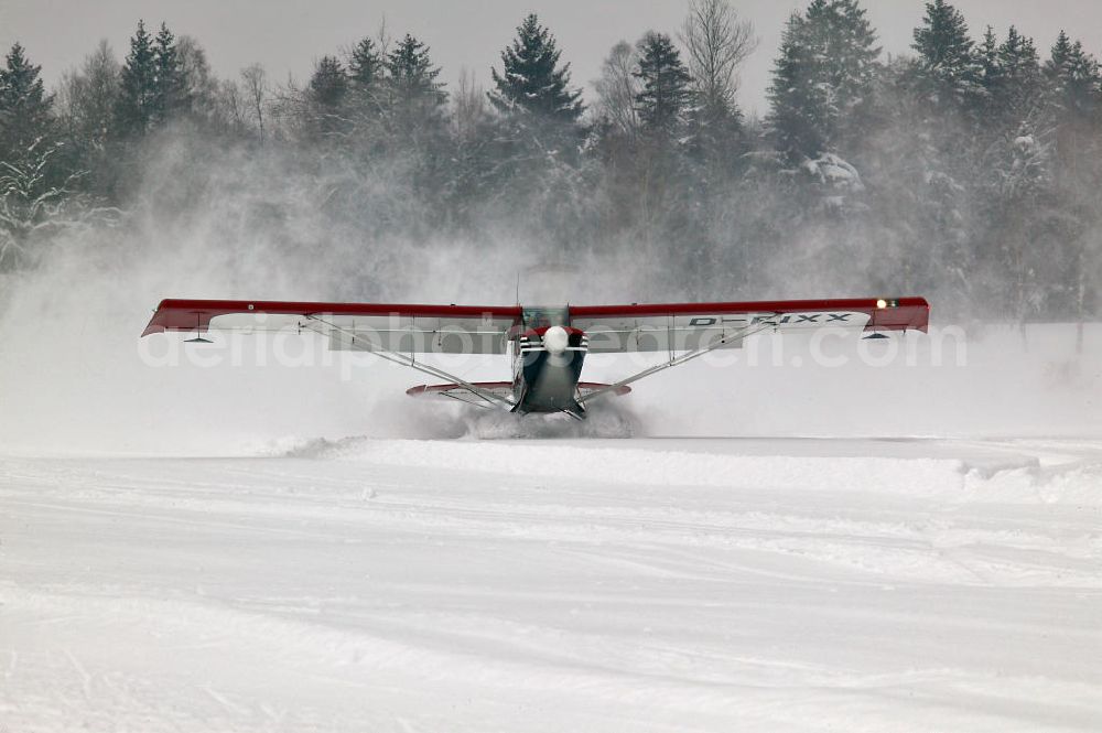 Isny im Allgäu from the bird's eye view: Kleinflugzeug / Flugzeug vom Typ Aviat Husky mit Rad-Ski-Fahrwerk über den mit Schnee bedecktem Segelfluggelände Isny-Rotmoos in Baden-Württemberg. Small aircraft over the Isny-Rotmoos glider airfield in Baden-Wuerttemberg.