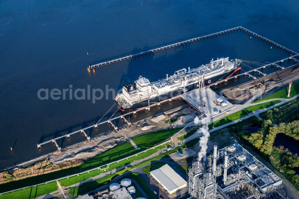 Stade from above - Water bridge with pipeline systems of the LNG natural gas and liquid gas terminal and unloading quay with the special ship Energos Force (formerly Transgas Force) docking on the banks of the Elbe in the district of Buetzfleth in Stade in the state Lower Saxony, Germany