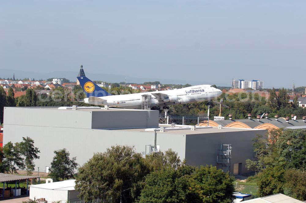 Aerial photograph SPEYER - Blick auf die LUFTHANSA BOEING 747 auf dem Gelände des Technik-Museum Speyer. Es befindet sich in der Nähe des Speyerer Stadtzentrums am Flugplatz Speyer. Es präsentiert auf einer Hallenfläche von 15.000 m² und 100.000 m² Freigelände eine große Anzahl zum Teil besonderer technischer Konstruktionen aus dem Fahrzeug- und Flugzeugbau. Des Weiteren befinden sich auf dem Museumsgelände das so genannte Marinehaus und ein Modellbaumuseum sowie ein IMAX-Dome-Filmtheater mit einer 24 m durchmessenden kuppelförmigen Leinwand (Projektionsfläche ca. 1000 m²). Im Forum des Museums können sich Besucher kostenlos über die Transporte einiger größerer Ausstellungsobjekte zum Technik-Museum Speyer und zum Auto- und Technikmuseum Sinsheim informieren. Das Hauptgebäude, die denkmalgeschützte, riesige Liller Halle, war früher der Bahnhof der französischen Stadt Lille. 1915 nach Deutschland transportiert, diente sie als Produktionshalle für die Pfalz-Flugzeugwerke und später mehrere Jahrzehnte als Panzerhalle für die Aufklärungspanzer eines französischen leichten Panzeraufklärungsregiments, dem traditionsreichen letzten Spahi-Regiment 1er Spahis. Dieses nutzte bis 1984 das heutige Museumsgelände als Kaserne.