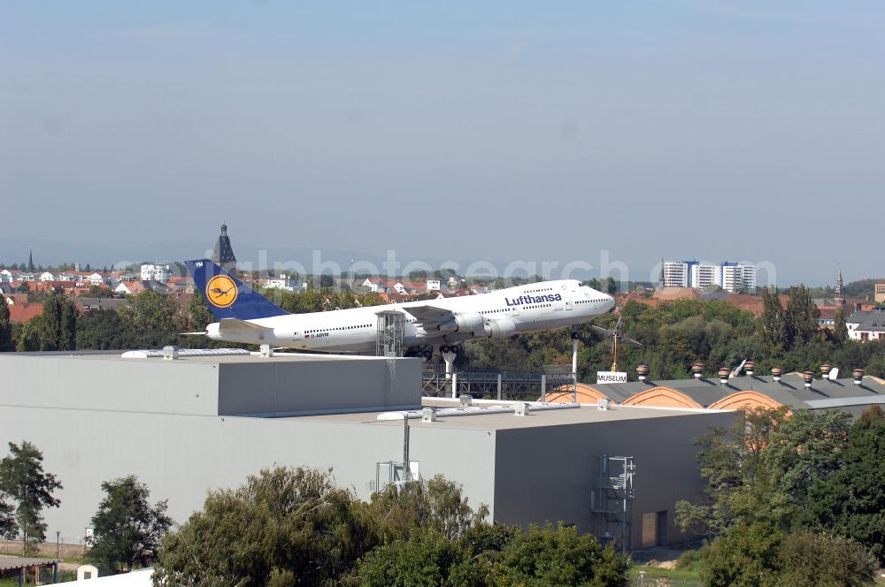 SPEYER from above - Blick auf die LUFTHANSA BOEING 747 auf dem Gelände des Technik-Museum Speyer. Es befindet sich in der Nähe des Speyerer Stadtzentrums am Flugplatz Speyer. Es präsentiert auf einer Hallenfläche von 15.000 m² und 100.000 m² Freigelände eine große Anzahl zum Teil besonderer technischer Konstruktionen aus dem Fahrzeug- und Flugzeugbau. Des Weiteren befinden sich auf dem Museumsgelände das so genannte Marinehaus und ein Modellbaumuseum sowie ein IMAX-Dome-Filmtheater mit einer 24 m durchmessenden kuppelförmigen Leinwand (Projektionsfläche ca. 1000 m²). Im Forum des Museums können sich Besucher kostenlos über die Transporte einiger größerer Ausstellungsobjekte zum Technik-Museum Speyer und zum Auto- und Technikmuseum Sinsheim informieren. Das Hauptgebäude, die denkmalgeschützte, riesige Liller Halle, war früher der Bahnhof der französischen Stadt Lille. 1915 nach Deutschland transportiert, diente sie als Produktionshalle für die Pfalz-Flugzeugwerke und später mehrere Jahrzehnte als Panzerhalle für die Aufklärungspanzer eines französischen leichten Panzeraufklärungsregiments, dem traditionsreichen letzten Spahi-Regiment 1er Spahis. Dieses nutzte bis 1984 das heutige Museumsgelände als Kaserne.