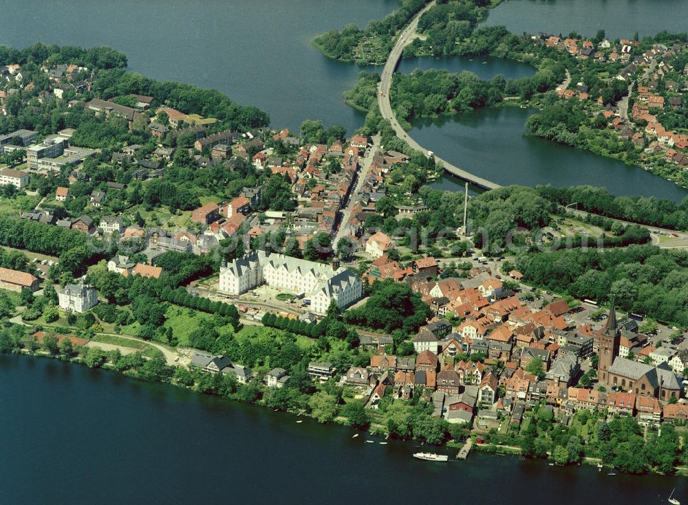 Aerial image PLÖN - 22.06.2004 PLÖN Plön besitzt seit 1236 Stadtrechte; ist seit dem 17. Jh. Residenz der Herzöge von Schleswig-Holstein-Sonderburg-Plön.Plön ist die Kreisstadt des Kreises Plön in Schleswig-Holstein und hat etwa 13.000 Einwohner. Sie liegt direkt am größten Binnensee Schleswig-Holsteins, dem Großen Plöner See. Wahrzeichen der Stadt ist das Schloss, das im 17. Jahrhundert erbaut wurde. Plön besitzt ein Gymnasium mit 300-jähriger Geschichte, ist Standort einer Marineunteroffizierschule und Sitz des Max-Planck-Instituts für Evolutionsbiologie. Die in die hügelige Seenlandschaft der Holsteinischen Schweiz eingebettete Stadt hat auch touristische Bedeutung. Das Plöner Schloss wurde 2001 unter der Landesregierung von Heide Simonis geschlossen und an den Optikerkonzern Fielmann verkauft. Dieser hat dort nach umfangreichen Restaurierungsarbeiten im Oktober 2006 eine Akademie für das Optikerhandwerk eröffnet. Es handelt sich um ein gemeinnütziges Schulungszentrum für die gesamte Augenoptik. Dies bedeutet für die Stadt Plön eine Stärkung der Wirtschaftskraft und eine herausragende Werbung, auch über die Landesgrenzen hinaus. Zum Schloss gehört das weitläufige Schlossgebiet, das zu den schönsten Schlossanlagen Schleswig-Holsteins gehört. Aufwendig restaurierte historische Gebäude (z.B. Prinzenhaus, Alte Schwimmhalle, Uhrenhaus), schattige Alleen und alter Baumbestand laden zum Erkunden und Flanieren ein.