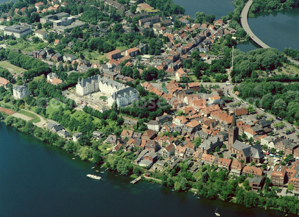 Aerial photograph PLÖN - 22.06.2004 PLÖN Plön besitzt seit 1236 Stadtrechte; ist seit dem 17. Jh. Residenz der Herzöge von Schleswig-Holstein-Sonderburg-Plön.Plön ist die Kreisstadt des Kreises Plön in Schleswig-Holstein und hat etwa 13.000 Einwohner. Sie liegt direkt am größten Binnensee Schleswig-Holsteins, dem Großen Plöner See. Wahrzeichen der Stadt ist das Schloss, das im 17. Jahrhundert erbaut wurde. Plön besitzt ein Gymnasium mit 300-jähriger Geschichte, ist Standort einer Marineunteroffizierschule und Sitz des Max-Planck-Instituts für Evolutionsbiologie. Die in die hügelige Seenlandschaft der Holsteinischen Schweiz eingebettete Stadt hat auch touristische Bedeutung. Das Plöner Schloss wurde 2001 unter der Landesregierung von Heide Simonis geschlossen und an den Optikerkonzern Fielmann verkauft. Dieser hat dort nach umfangreichen Restaurierungsarbeiten im Oktober 2006 eine Akademie für das Optikerhandwerk eröffnet. Es handelt sich um ein gemeinnütziges Schulungszentrum für die gesamte Augenoptik. Dies bedeutet für die Stadt Plön eine Stärkung der Wirtschaftskraft und eine herausragende Werbung, auch über die Landesgrenzen hinaus. Zum Schloss gehört das weitläufige Schlossgebiet, das zu den schönsten Schlossanlagen Schleswig-Holsteins gehört. Aufwendig restaurierte historische Gebäude (z.B. Prinzenhaus, Alte Schwimmhalle, Uhrenhaus), schattige Alleen und alter Baumbestand laden zum Erkunden und Flanieren ein.