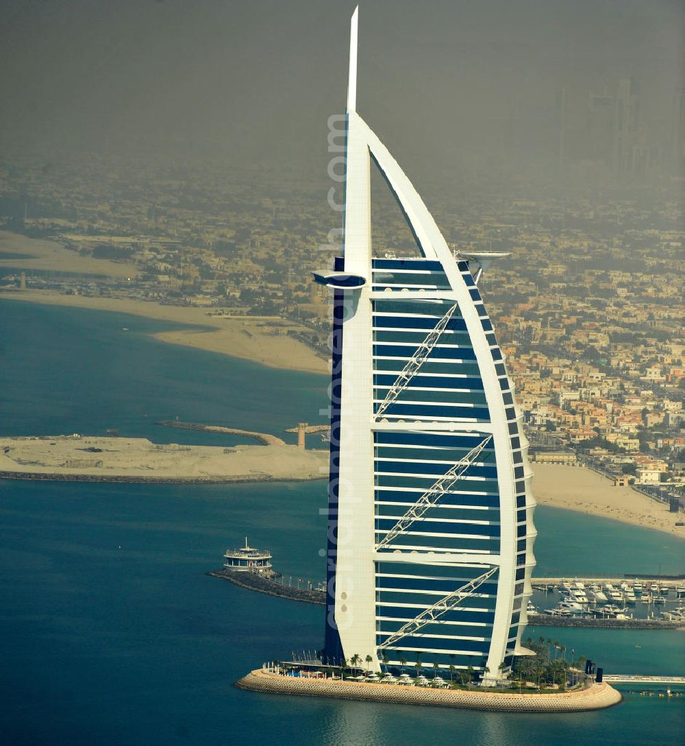 DUBAI / DUBAYY from the bird's eye view: Blick auf das Luxus- Hotel Burj al Arab am Persischen Golf in Dubai. Der architektonisch einprägsame Bau der Jumeirah Group ist eines der luxuriösesten und teuersten Hotels der Welt. Mit einer Höhe von 321 Metern ist es nach dem Rose Tower das höchste reine Hotelgebäude der Welt und ein Wahrzeichen der emiratischen Stadt Dubai. Der Entwurf stammt von Tom Wright / Atkins Middle East. Ausdrücklicher Wunsch der Bauherren war es, eine Architekturikone zu schaffen, die ein Identifikationsmerkmal für Dubai wird. Der Entwurf hat die Form des Segels einer modernen Yacht und soll die Vergangenheit als Seehandelszentrum sowie die Zukunftsorientierung Dubais symbolisieren. Luxury hotel Burj al Arab on Persian Gulf in Dubai.