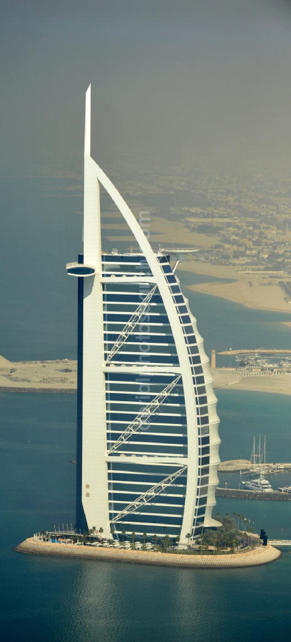 DUBAI / DUBAYY from above - Blick auf das Luxus- Hotel Burj al Arab am Persischen Golf in Dubai. Der architektonisch einprägsame Bau der Jumeirah Group ist eines der luxuriösesten und teuersten Hotels der Welt. Mit einer Höhe von 321 Metern ist es nach dem Rose Tower das höchste reine Hotelgebäude der Welt und ein Wahrzeichen der emiratischen Stadt Dubai. Der Entwurf stammt von Tom Wright / Atkins Middle East. Ausdrücklicher Wunsch der Bauherren war es, eine Architekturikone zu schaffen, die ein Identifikationsmerkmal für Dubai wird. Der Entwurf hat die Form des Segels einer modernen Yacht und soll die Vergangenheit als Seehandelszentrum sowie die Zukunftsorientierung Dubais symbolisieren. Luxury hotel Burj al Arab on Persian Gulf in Dubai.