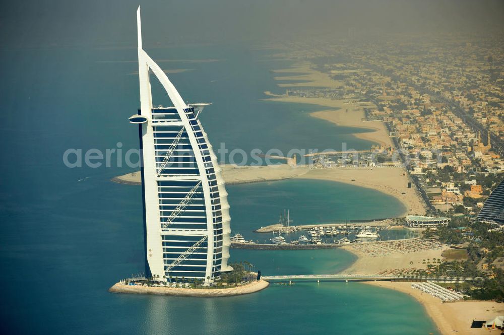 Aerial photograph DUBAI / DUBAYY - Blick auf das Luxus- Hotel Burj al Arab am Persischen Golf in Dubai. Der architektonisch einprägsame Bau der Jumeirah Group ist eines der luxuriösesten und teuersten Hotels der Welt. Mit einer Höhe von 321 Metern ist es nach dem Rose Tower das höchste reine Hotelgebäude der Welt und ein Wahrzeichen der emiratischen Stadt Dubai. Der Entwurf stammt von Tom Wright / Atkins Middle East. Ausdrücklicher Wunsch der Bauherren war es, eine Architekturikone zu schaffen, die ein Identifikationsmerkmal für Dubai wird. Der Entwurf hat die Form des Segels einer modernen Yacht und soll die Vergangenheit als Seehandelszentrum sowie die Zukunftsorientierung Dubais symbolisieren. Luxury hotel Burj al Arab on Persian Gulf in Dubai.