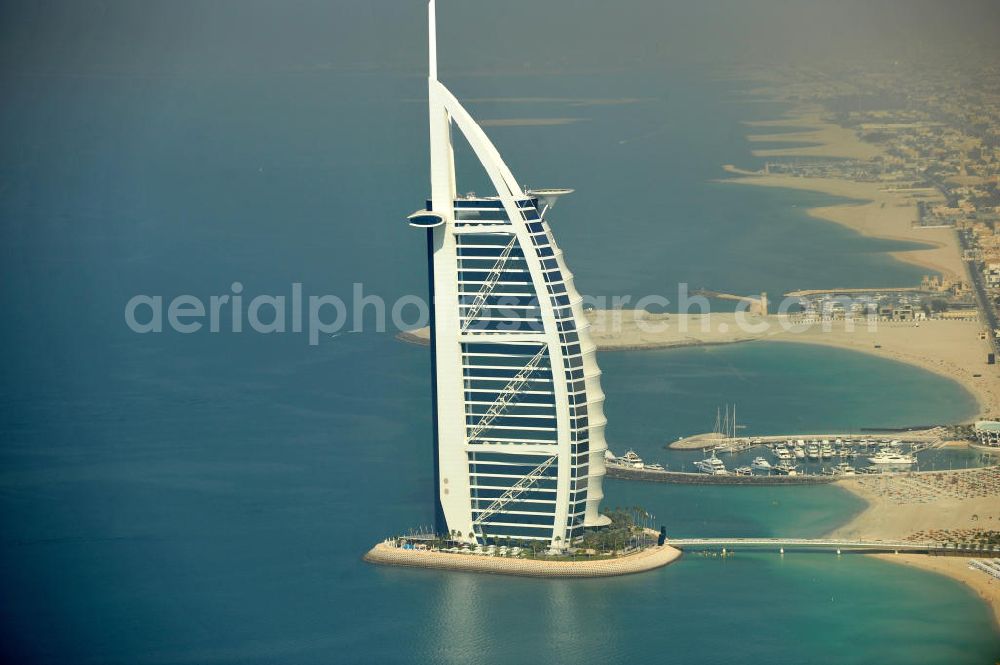 DUBAI / DUBAYY from above - Blick auf das Luxus- Hotel Burj al Arab am Persischen Golf in Dubai. Der architektonisch einprägsame Bau der Jumeirah Group ist eines der luxuriösesten und teuersten Hotels der Welt. Mit einer Höhe von 321 Metern ist es nach dem Rose Tower das höchste reine Hotelgebäude der Welt und ein Wahrzeichen der emiratischen Stadt Dubai. Der Entwurf stammt von Tom Wright / Atkins Middle East. Ausdrücklicher Wunsch der Bauherren war es, eine Architekturikone zu schaffen, die ein Identifikationsmerkmal für Dubai wird. Der Entwurf hat die Form des Segels einer modernen Yacht und soll die Vergangenheit als Seehandelszentrum sowie die Zukunftsorientierung Dubais symbolisieren. Luxury hotel Burj al Arab on Persian Gulf in Dubai.