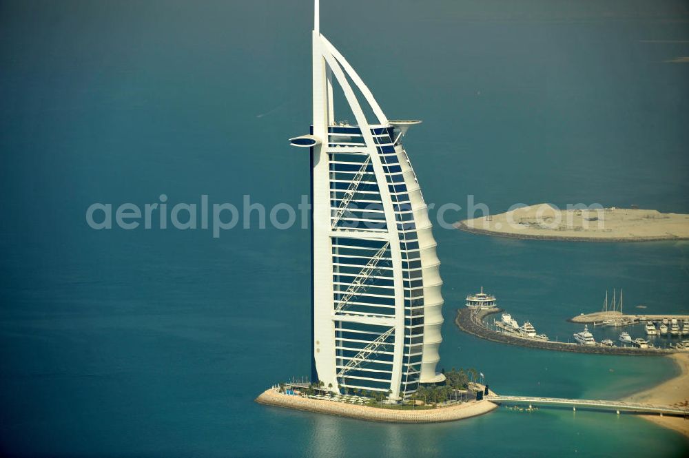 DUBAI / DUBAYY from the bird's eye view: Blick auf das Luxus- Hotel Burj al Arab am Persischen Golf in Dubai. Der architektonisch einprägsame Bau der Jumeirah Group ist eines der luxuriösesten und teuersten Hotels der Welt. Mit einer Höhe von 321 Metern ist es nach dem Rose Tower das höchste reine Hotelgebäude der Welt und ein Wahrzeichen der emiratischen Stadt Dubai. Der Entwurf stammt von Tom Wright / Atkins Middle East. Ausdrücklicher Wunsch der Bauherren war es, eine Architekturikone zu schaffen, die ein Identifikationsmerkmal für Dubai wird. Der Entwurf hat die Form des Segels einer modernen Yacht und soll die Vergangenheit als Seehandelszentrum sowie die Zukunftsorientierung Dubais symbolisieren. Luxury hotel Burj al Arab on Persian Gulf in Dubai.