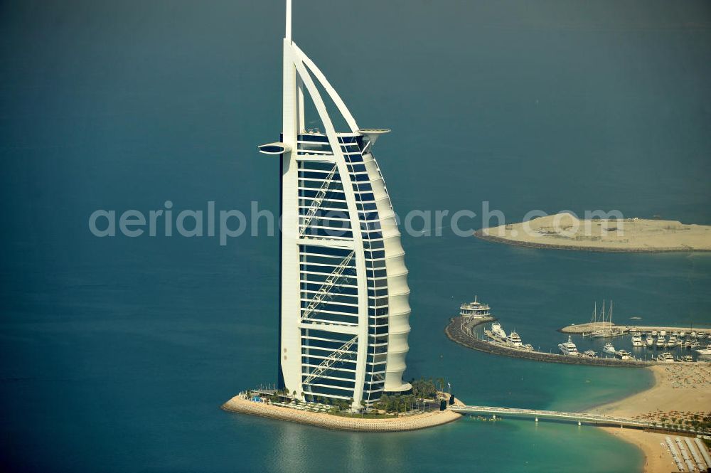 Aerial image DUBAI / DUBAYY - Blick auf das Luxus- Hotel Burj al Arab am Persischen Golf in Dubai. Der architektonisch einprägsame Bau der Jumeirah Group ist eines der luxuriösesten und teuersten Hotels der Welt. Mit einer Höhe von 321 Metern ist es nach dem Rose Tower das höchste reine Hotelgebäude der Welt und ein Wahrzeichen der emiratischen Stadt Dubai. Der Entwurf stammt von Tom Wright / Atkins Middle East. Ausdrücklicher Wunsch der Bauherren war es, eine Architekturikone zu schaffen, die ein Identifikationsmerkmal für Dubai wird. Der Entwurf hat die Form des Segels einer modernen Yacht und soll die Vergangenheit als Seehandelszentrum sowie die Zukunftsorientierung Dubais symbolisieren. Luxury hotel Burj al Arab on Persian Gulf in Dubai.