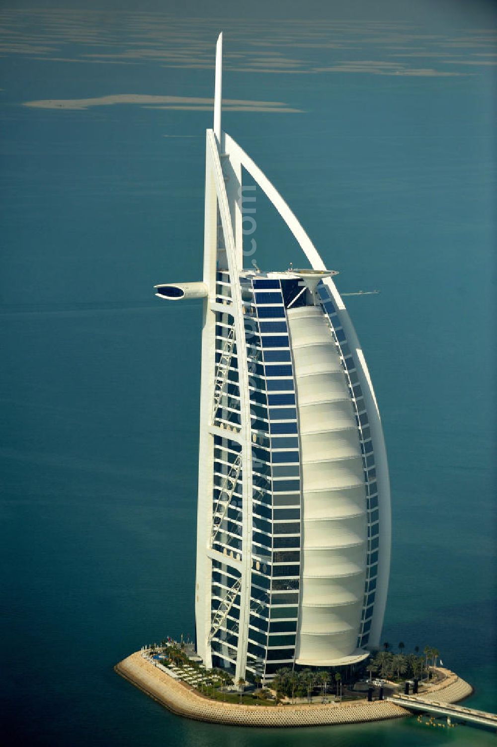 DUBAI / DUBAYY from the bird's eye view: Blick auf das Luxus- Hotel Burj al Arab am Persischen Golf in Dubai. Der architektonisch einprägsame Bau der Jumeirah Group ist eines der luxuriösesten und teuersten Hotels der Welt. Mit einer Höhe von 321 Metern ist es nach dem Rose Tower das höchste reine Hotelgebäude der Welt und ein Wahrzeichen der emiratischen Stadt Dubai. Der Entwurf stammt von Tom Wright / Atkins Middle East. Ausdrücklicher Wunsch der Bauherren war es, eine Architekturikone zu schaffen, die ein Identifikationsmerkmal für Dubai wird. Der Entwurf hat die Form des Segels einer modernen Yacht und soll die Vergangenheit als Seehandelszentrum sowie die Zukunftsorientierung Dubais symbolisieren. Luxury hotel Burj al Arab on Persian Gulf in Dubai.