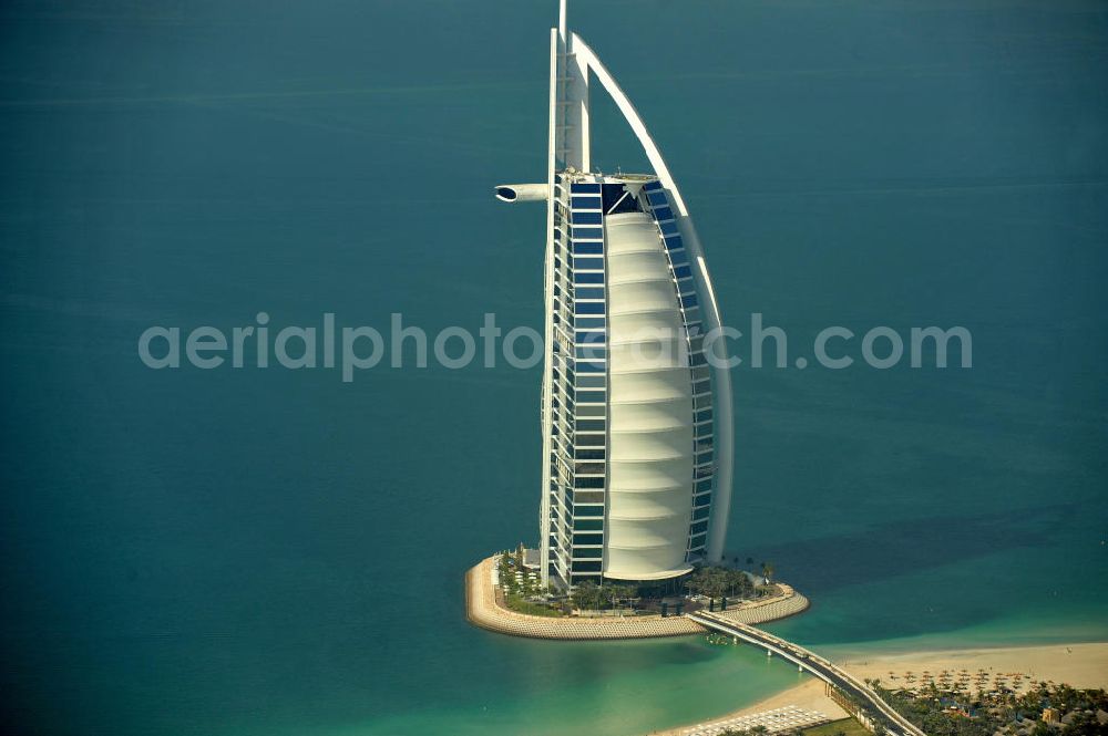 DUBAI / DUBAYY from the bird's eye view: Blick auf das Luxus- Hotel Burj al Arab am Persischen Golf in Dubai. Der architektonisch einprägsame Bau der Jumeirah Group ist eines der luxuriösesten und teuersten Hotels der Welt. Mit einer Höhe von 321 Metern ist es nach dem Rose Tower das höchste reine Hotelgebäude der Welt und ein Wahrzeichen der emiratischen Stadt Dubai. Der Entwurf stammt von Tom Wright / Atkins Middle East. Ausdrücklicher Wunsch der Bauherren war es, eine Architekturikone zu schaffen, die ein Identifikationsmerkmal für Dubai wird. Der Entwurf hat die Form des Segels einer modernen Yacht und soll die Vergangenheit als Seehandelszentrum sowie die Zukunftsorientierung Dubais symbolisieren. Luxury hotel Burj al Arab on Persian Gulf in Dubai.