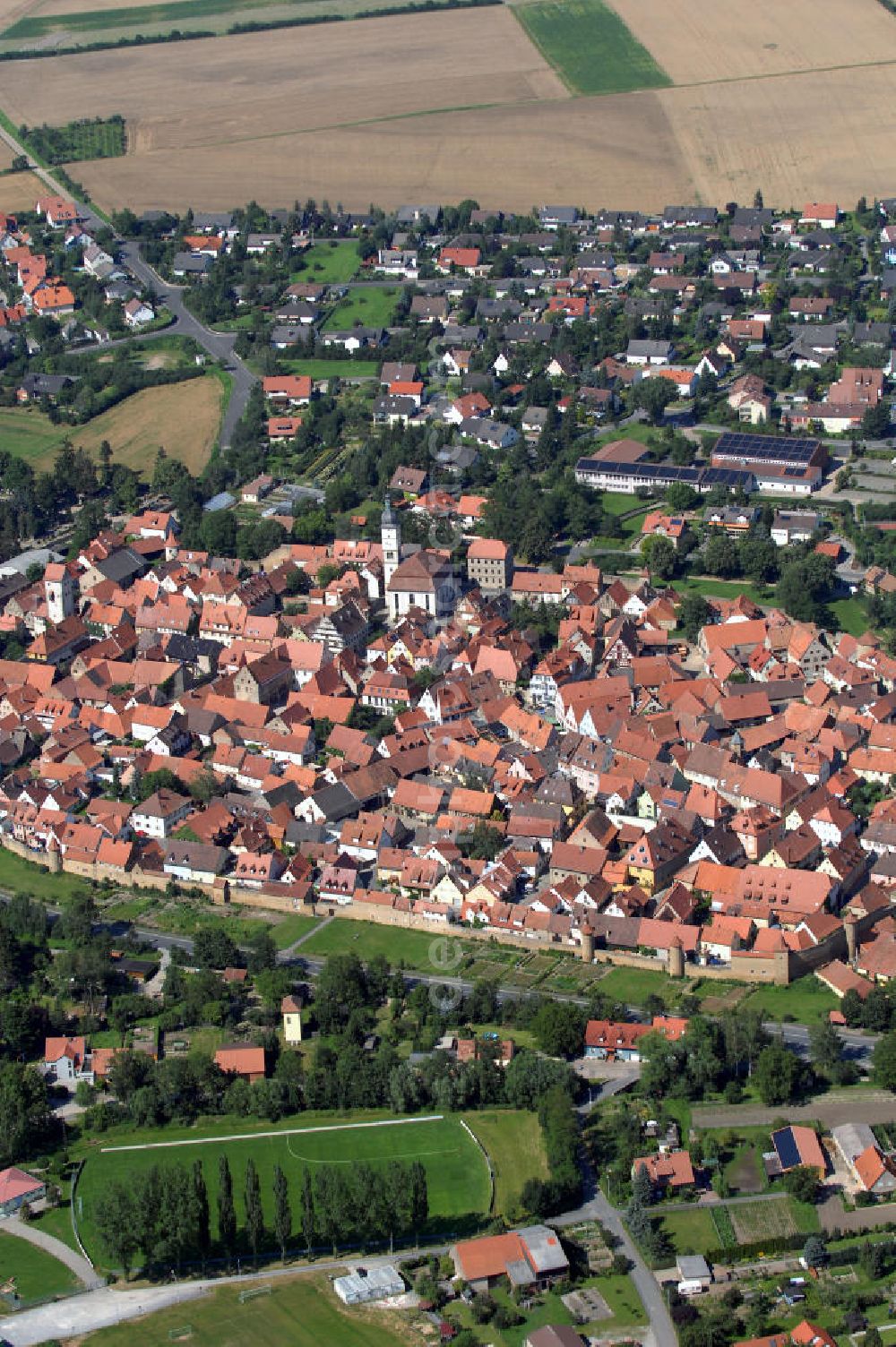 Aerial photograph Mainbernheim - Mainbernheim mit Kirche undseiner weitgehend intakten Stadtmauer. Sie hat zum größten Teil ein mittelalterliches Stadtbild mit einigen sorgfältig restaurierten Bürgerhäusern. Eine besondere Rarität ist der Arkadenfriedhof mit einer Friedhofskanzel außerhalb des Mauerrings der Stadt.