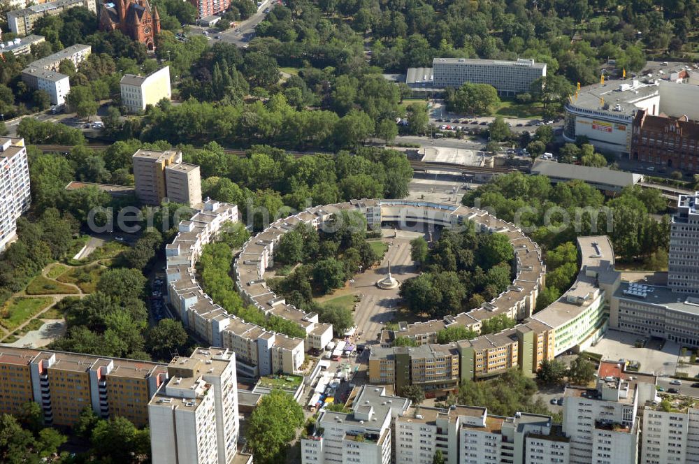 Aerial photograph Berlin - Blick auf den Mehringplatz in Friedrichshain-Kreuzberg. Der Mehringplatz ist einer von drei bedeutenden Plätzen, die bei der Stadterweiterung Berlins um 1730 angelegt wurden. Er bildet den südlichen Endpunkt der Friedrichstraße. Sein Kennzeichen ist ein Brunnen mit der 1843 errichteten Friedenssäule. Im Zweiten Weltkrieg wurde der Platz vollständig zerstört und danach mit veränderter Straßenführung und neuer Bebauung wieder hergestellt. Das Neubaugebiet um den Platz gilt heute als sozialer Brennpunkt und Präventionsgebiet.