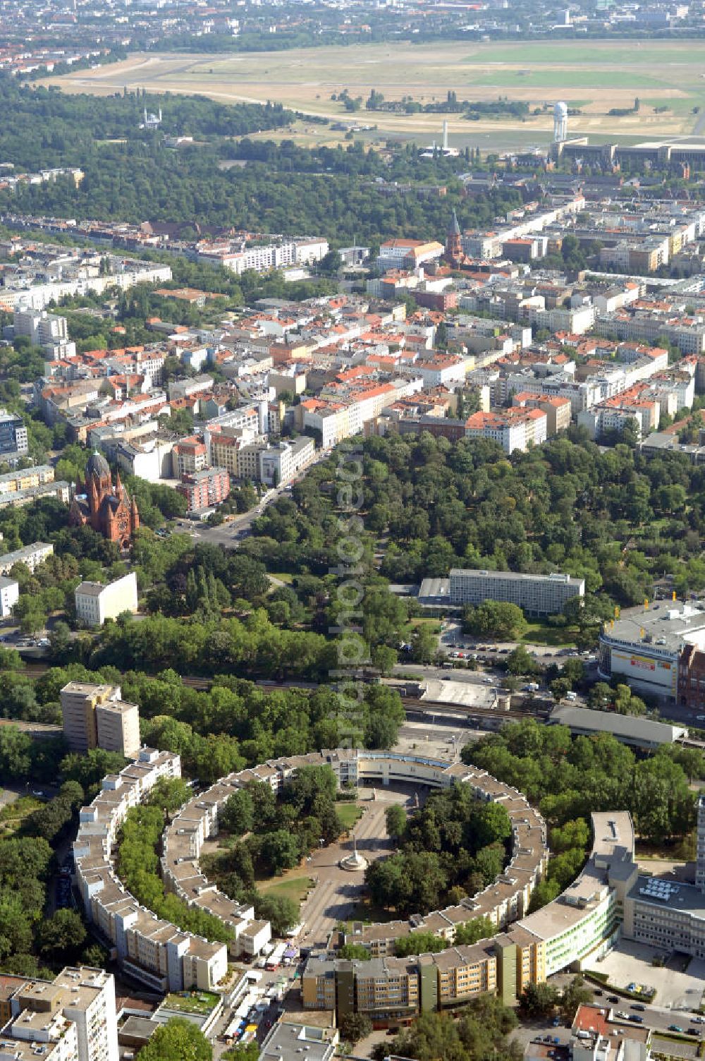 Berlin from above - Blick auf den Mehringplatz in Friedrichshain-Kreuzberg. Der Mehringplatz ist einer von drei bedeutenden Plätzen, die bei der Stadterweiterung Berlins um 1730 angelegt wurden. Er bildet den südlichen Endpunkt der Friedrichstraße. Sein Kennzeichen ist ein Brunnen mit der 1843 errichteten Friedenssäule. Im Zweiten Weltkrieg wurde der Platz vollständig zerstört und danach mit veränderter Straßenführung und neuer Bebauung wieder hergestellt. Das Neubaugebiet um den Platz gilt heute als sozialer Brennpunkt und Präventionsgebiet.